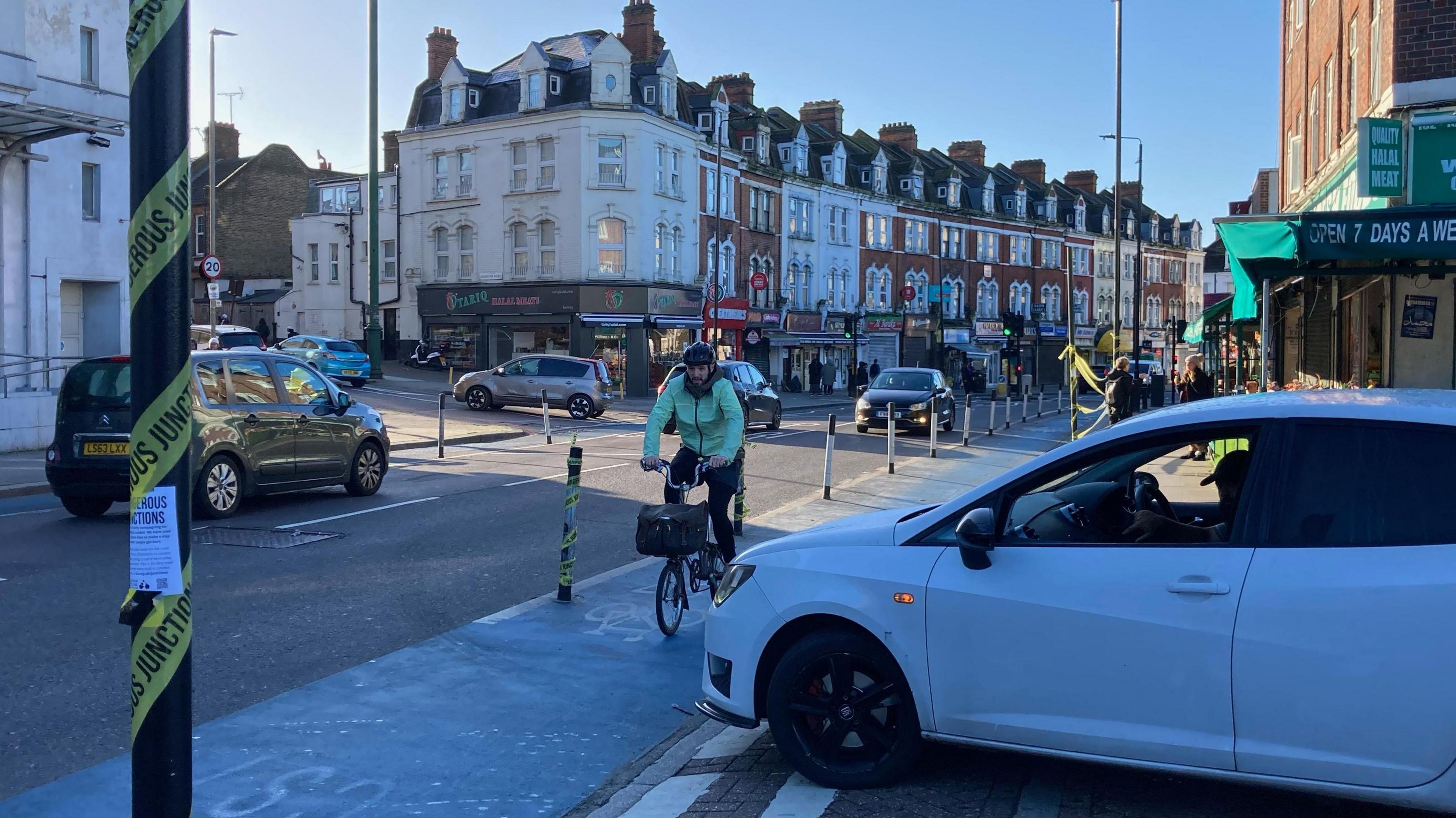 A cyclist pedals along the bike lane in front of a T-junction