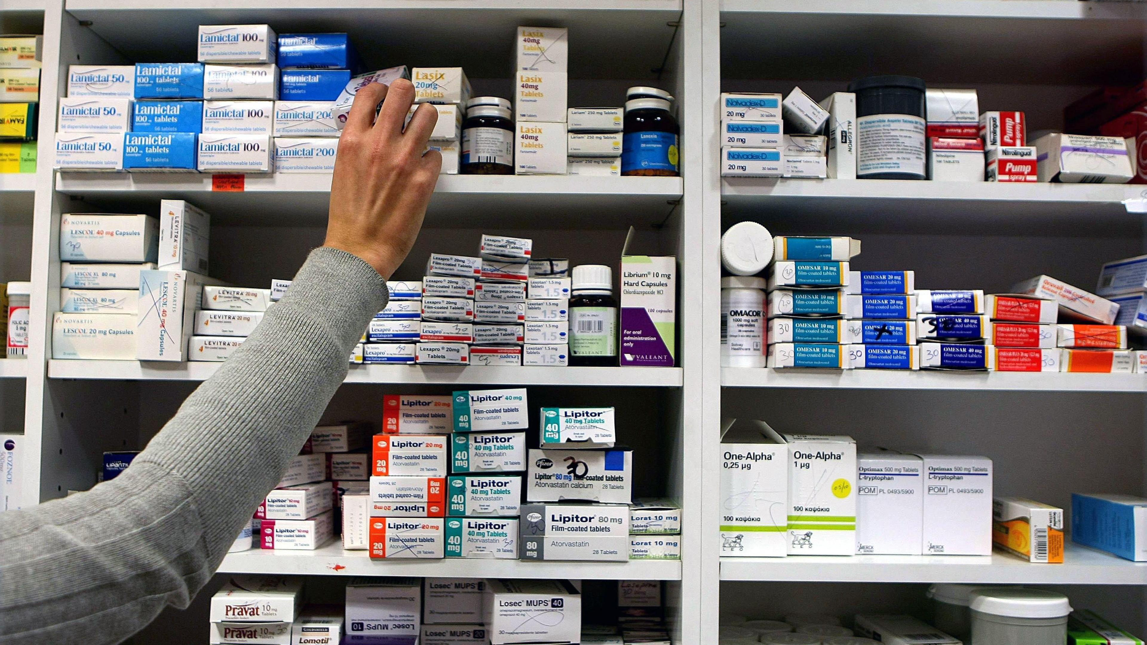 A pharmacist stocking shelves with piles of tablets at a chemist.