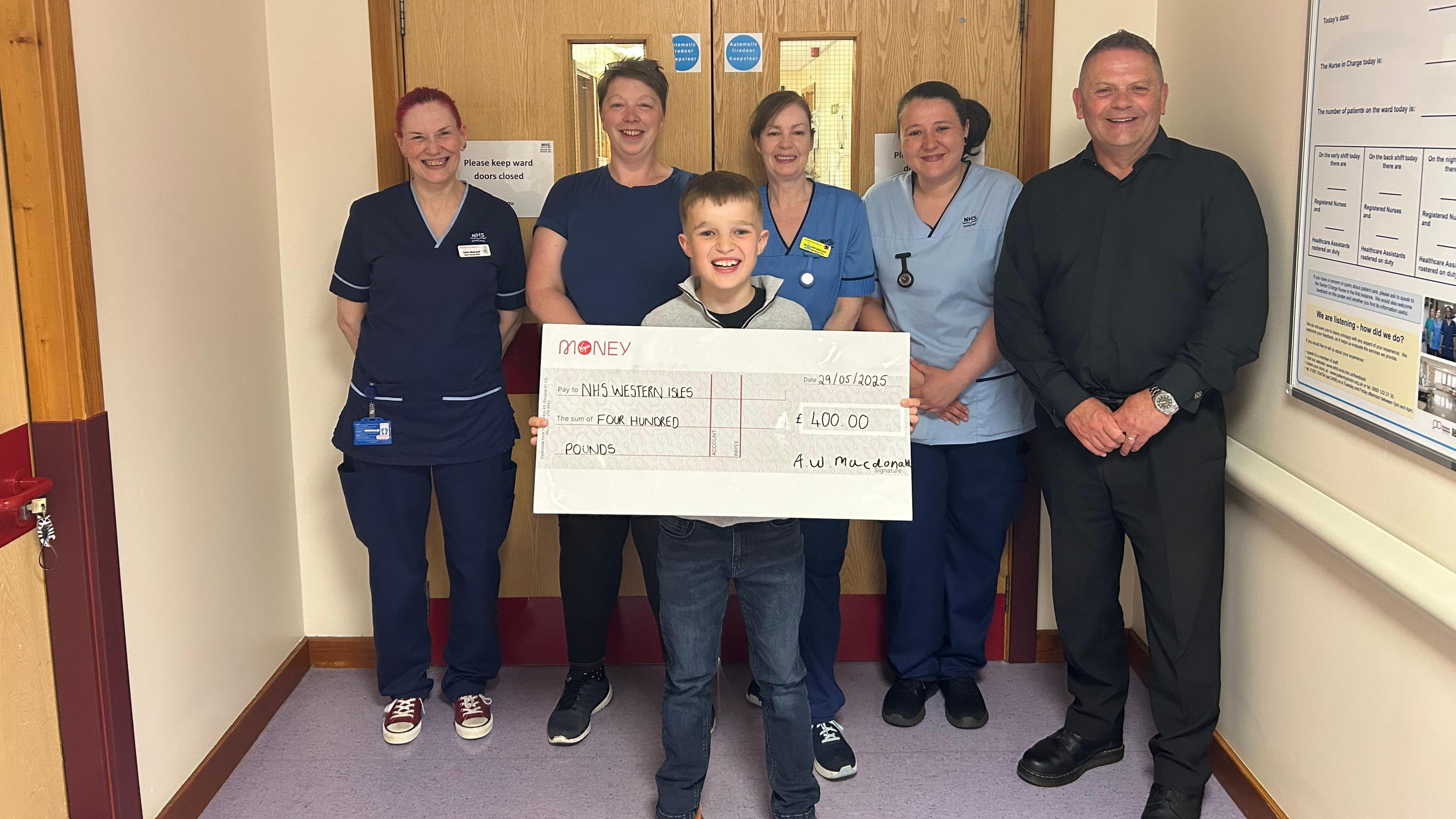 Aaron a' toirt seachad seic gu luchd-obrach NHS nan Eilean Siar