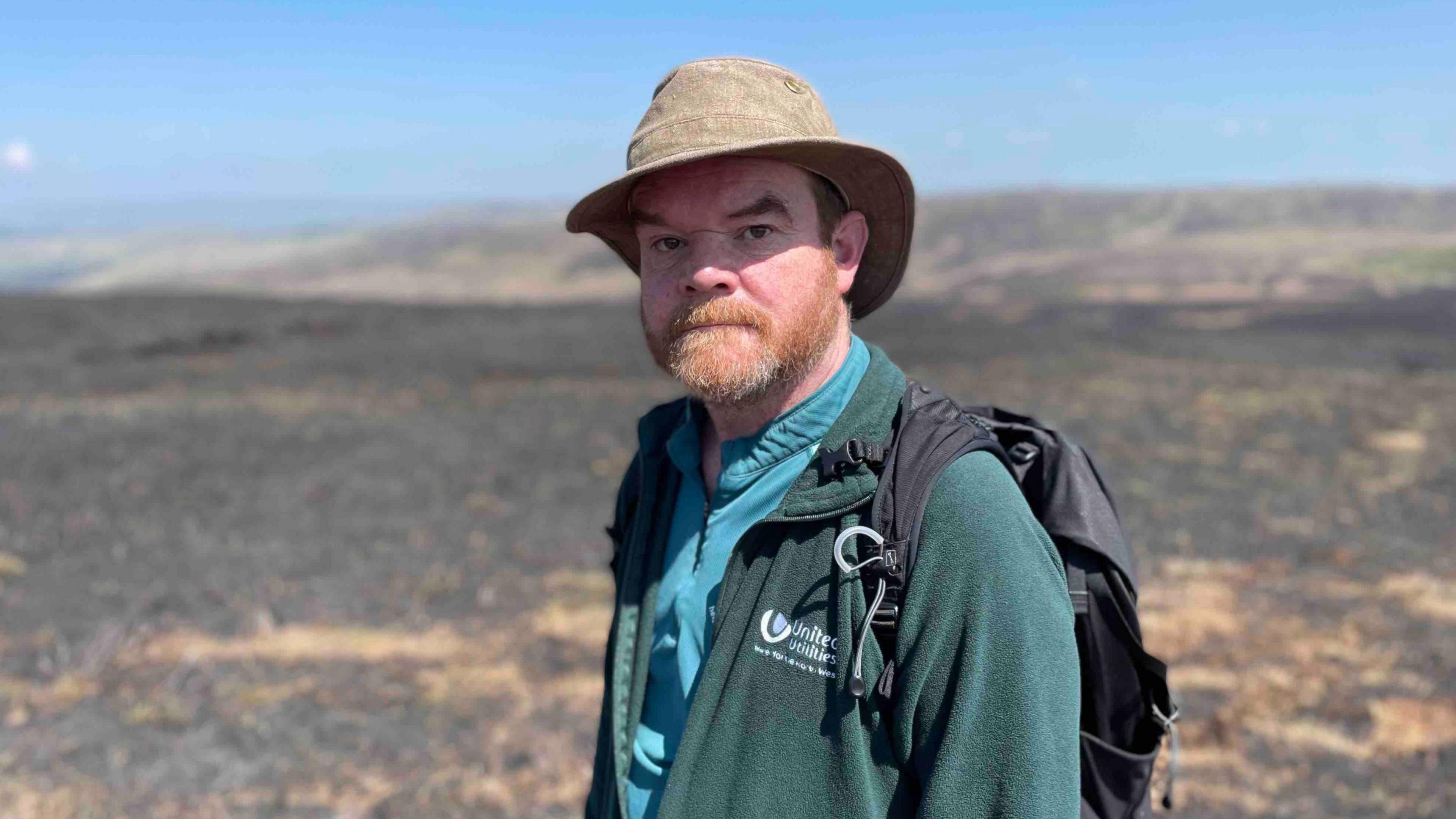 Ed Lawrance from United Utilities in the Goyt Valley is pictured wearing a sun hat, with scorched moorland behind him