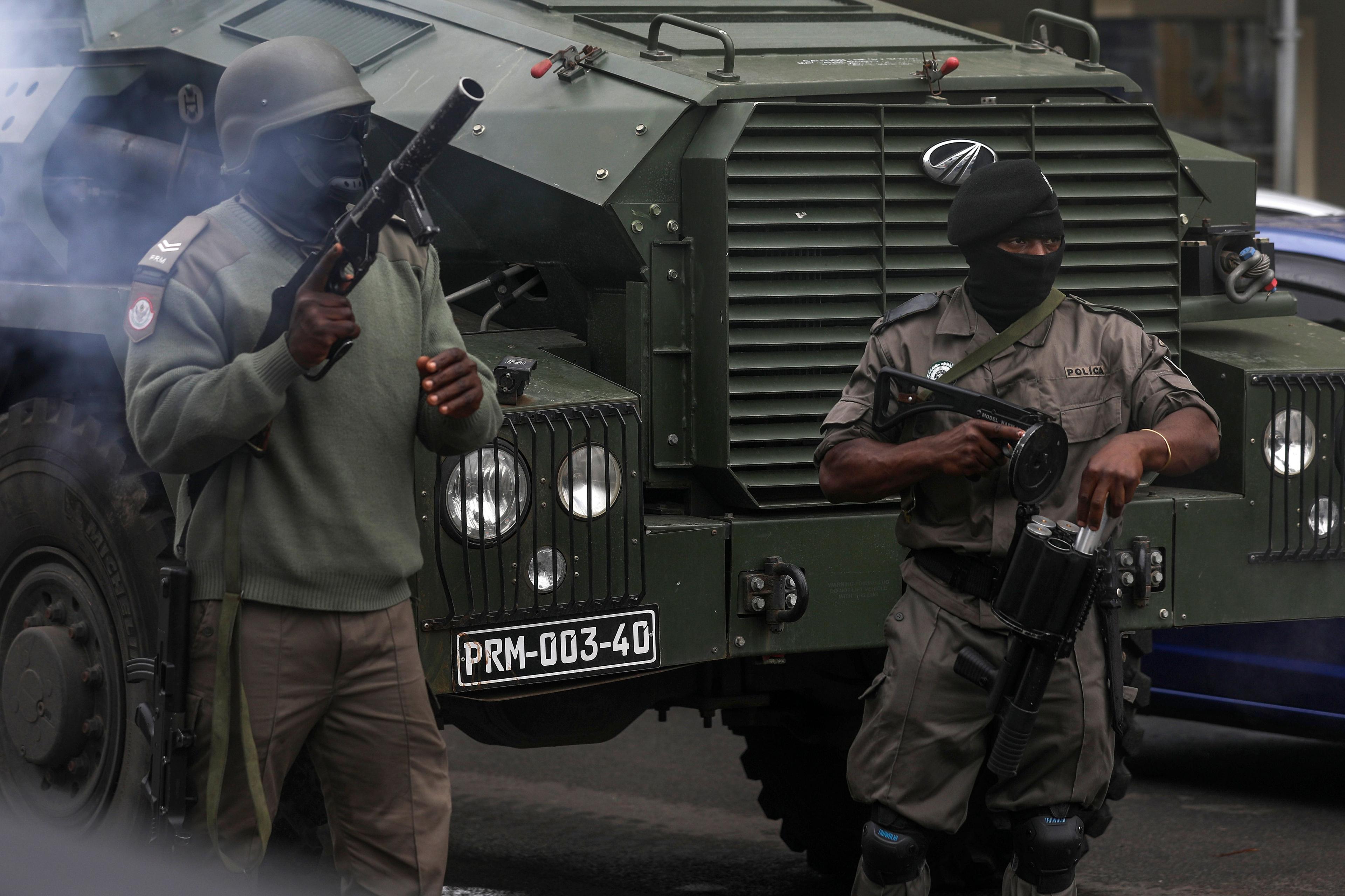 Two masked Mozambican police officers try to disperse people gathering to take part a march called by presidential candidate Venâncio Mondlane over the killing of two his supporters, in Maputo, Mozambique - Monday 21 October 2024