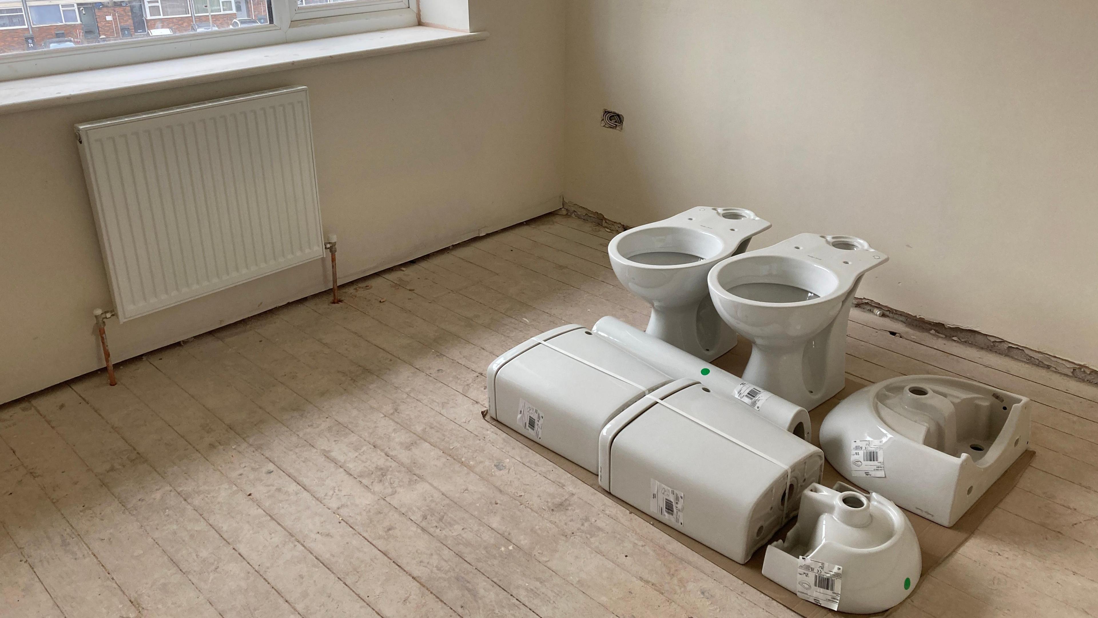 The picture shows a room inside one of the homes which is being refurbished. The walls have been re-plastered and new bathroom fittings are waiting to be installed. 