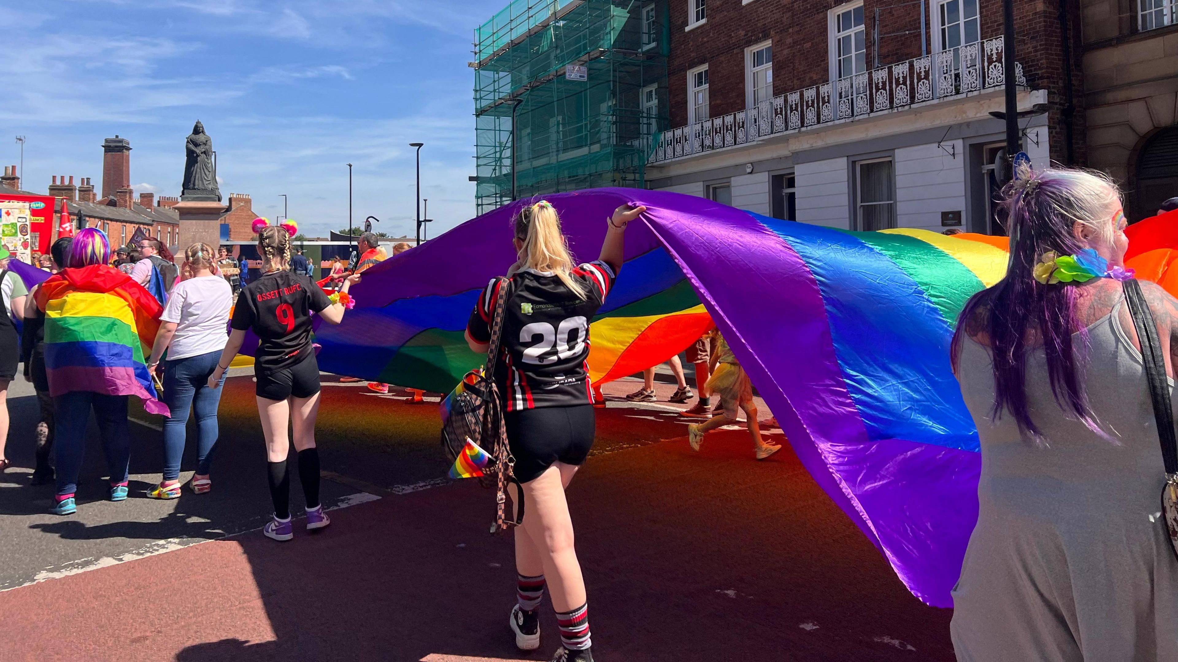 People taking part in the Pride parade carry a rainbow flag