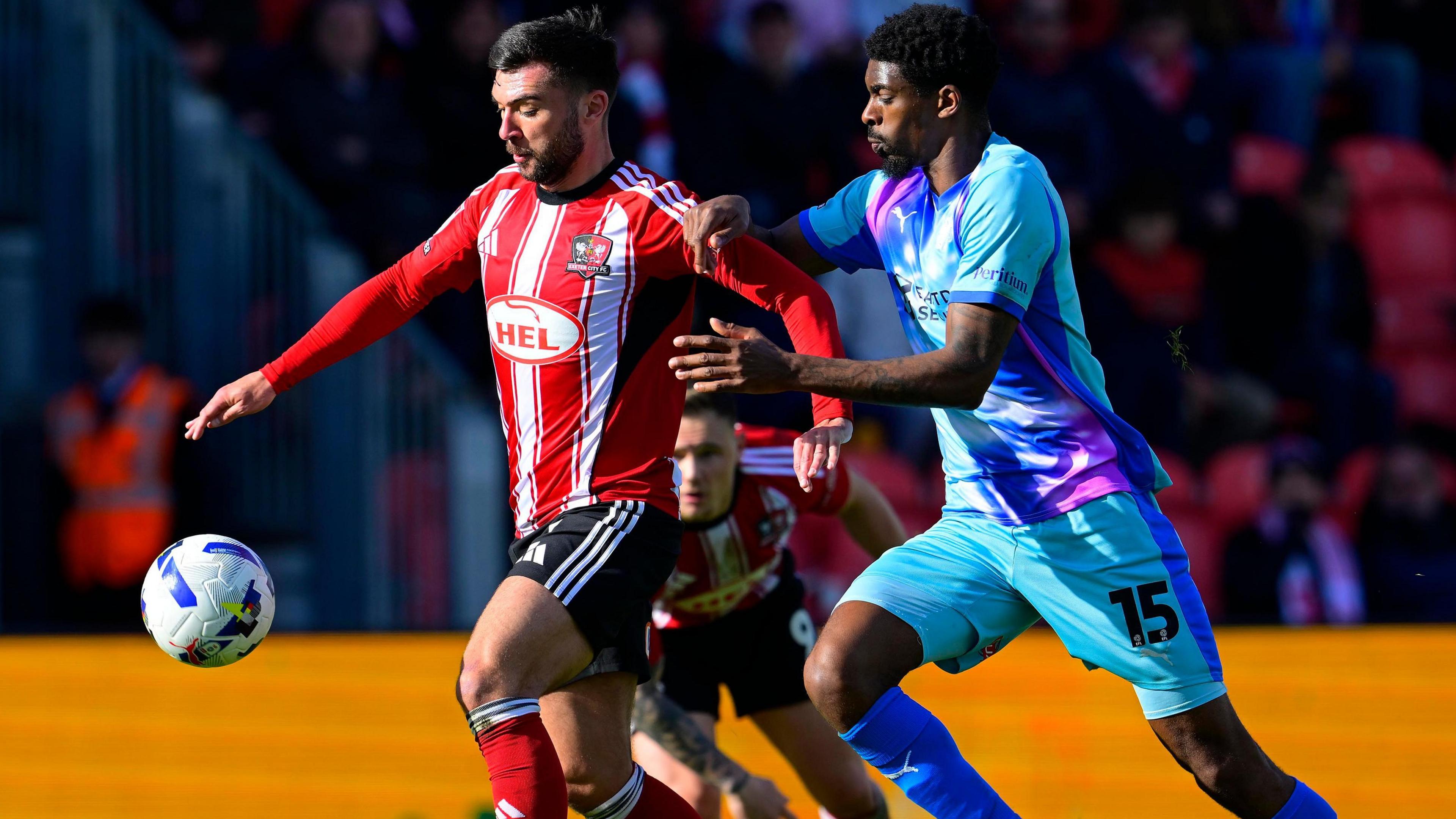 Reece Cole (left) and Tyreeq Bakinson challenge for a ball at Exeter City v Leyton Orient