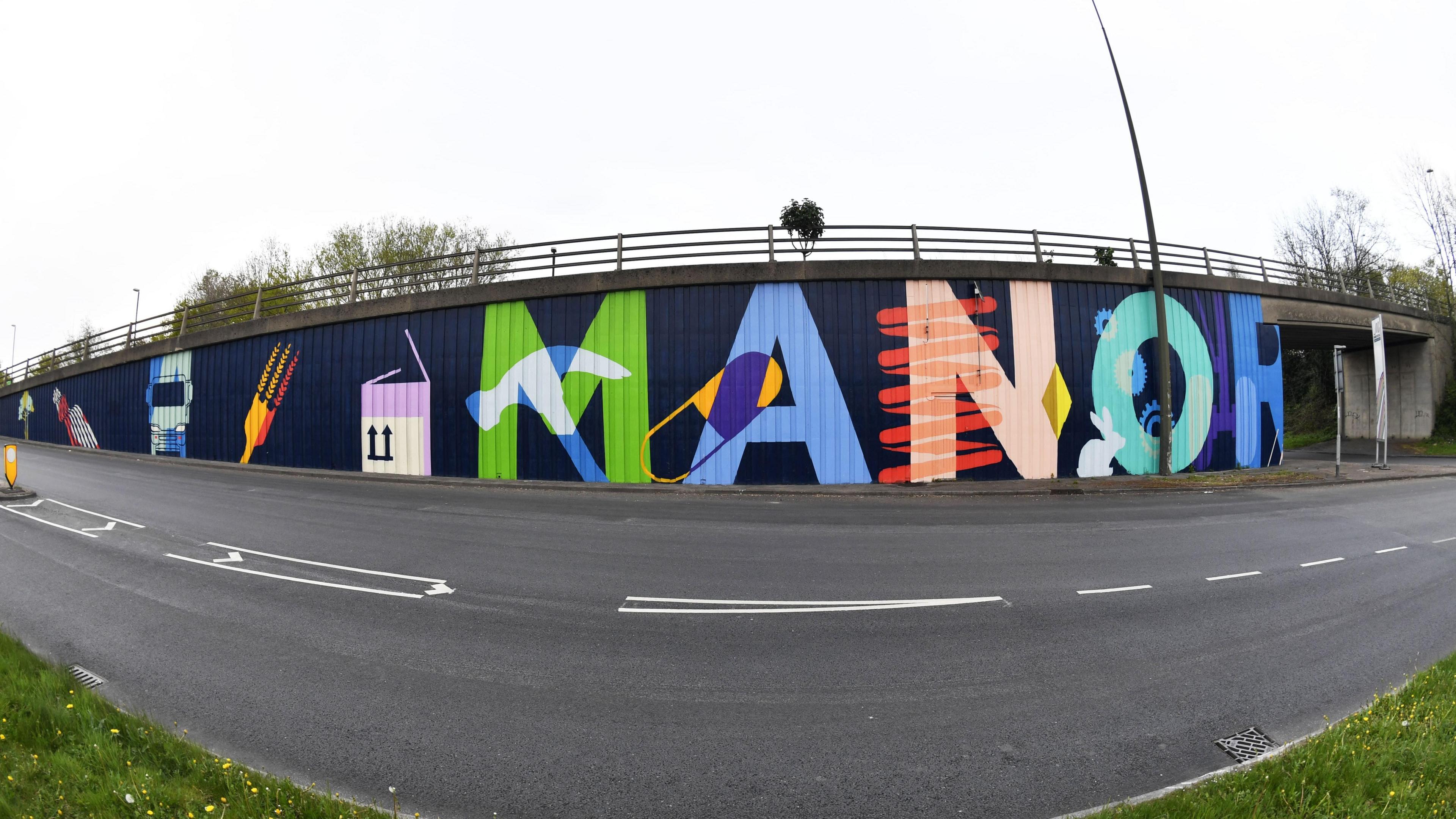 A multi-coloured mural on the side of a wall reading "MANOR" 