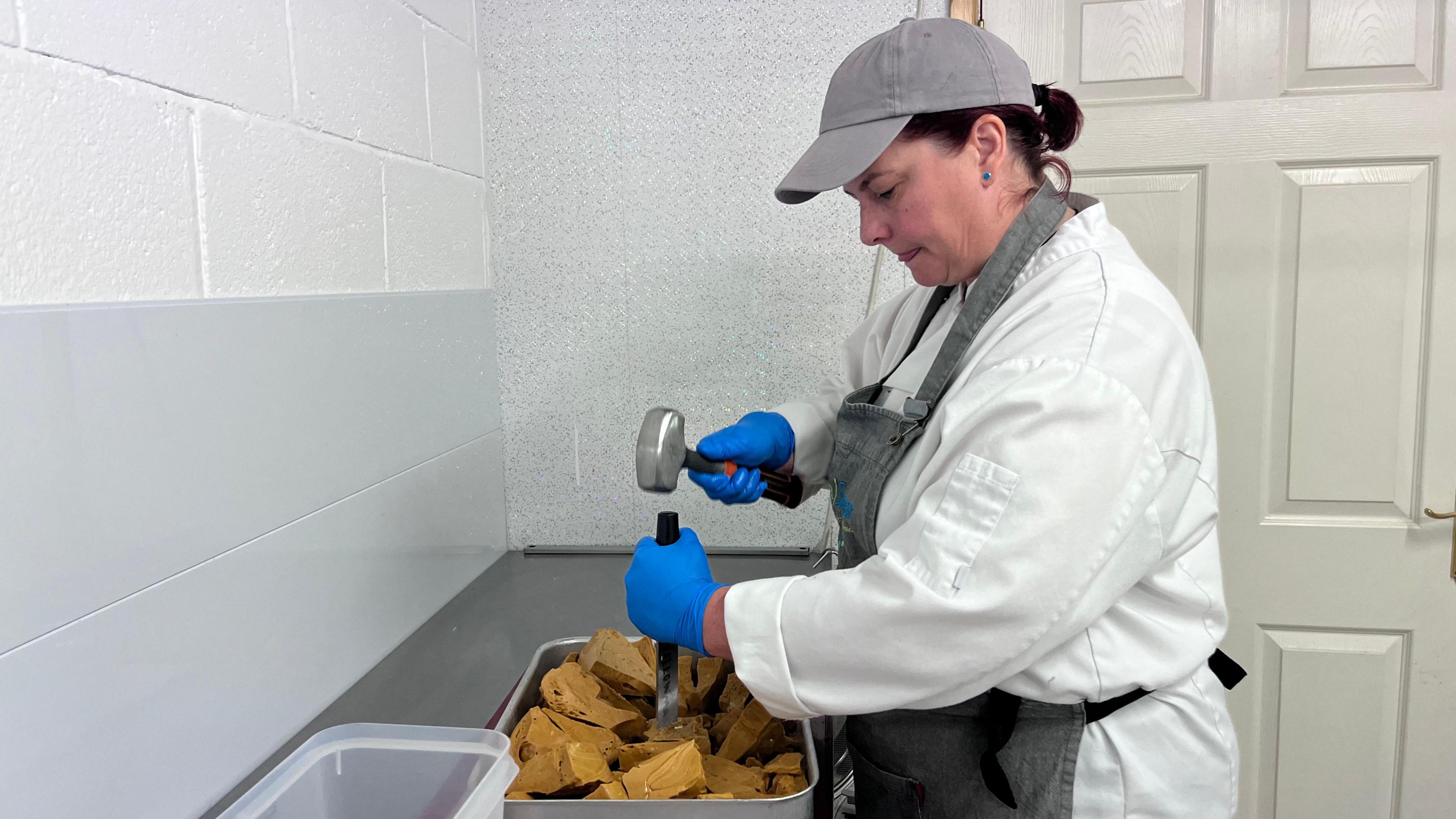 Linda McGibbon breaking yellow man with a hammer and chisel in her catering outfit. 