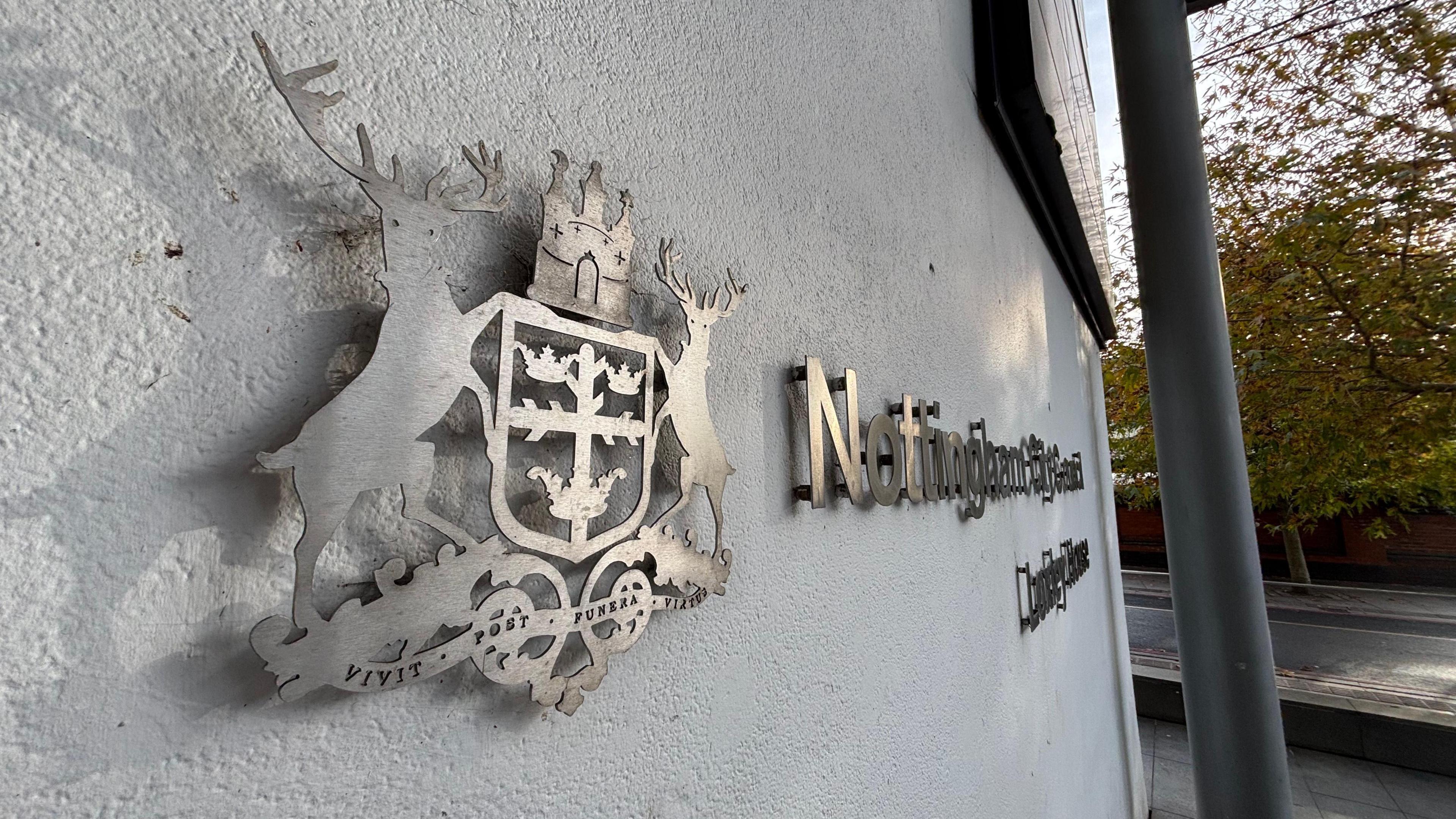 Nottingham City Council's headquarters building. A grey Nottingham City Council sign is set against a grey wall.