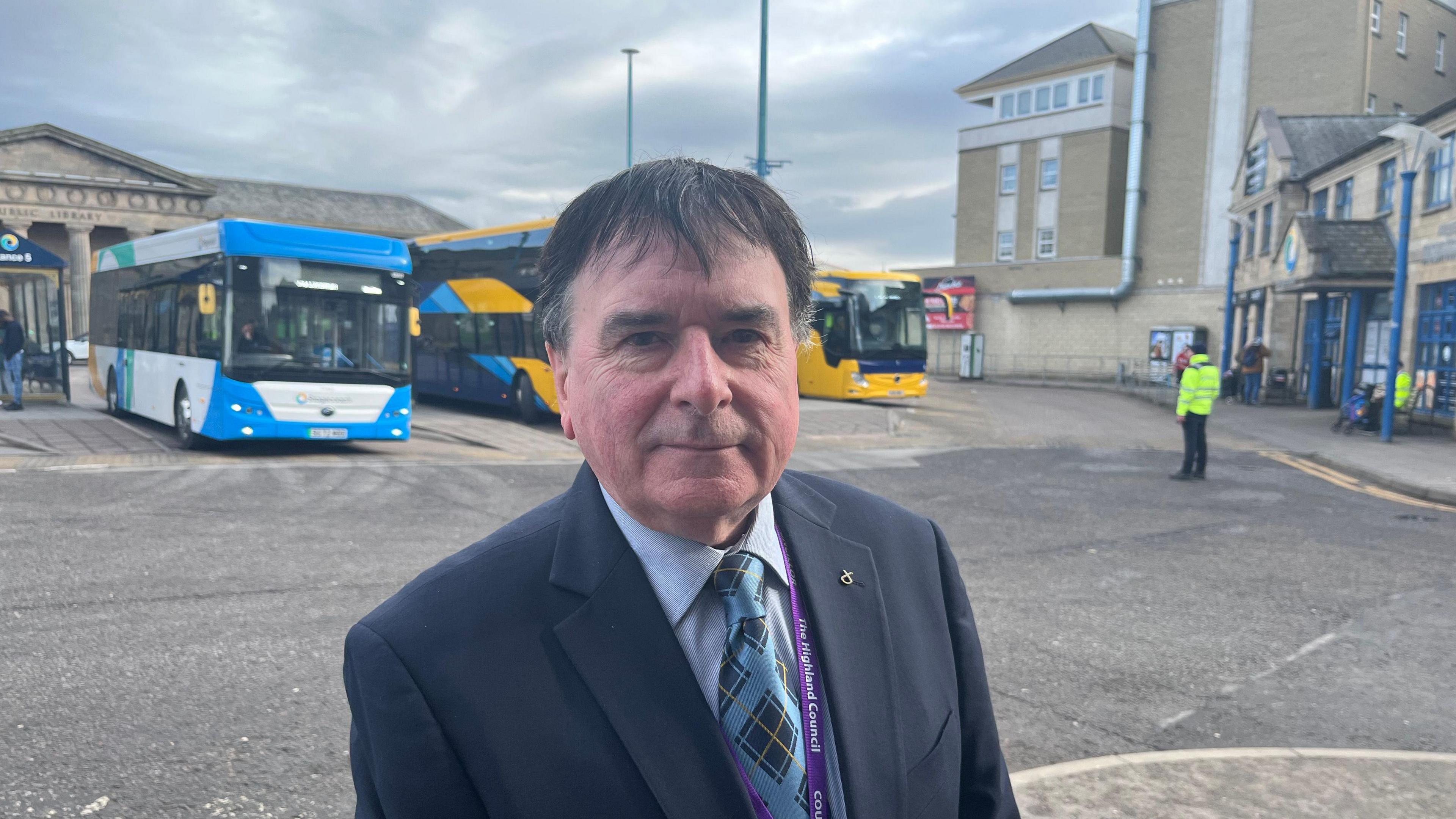 Ken Gowans na sheasamh aig stèisean nam busaichean an Inbhir Nis