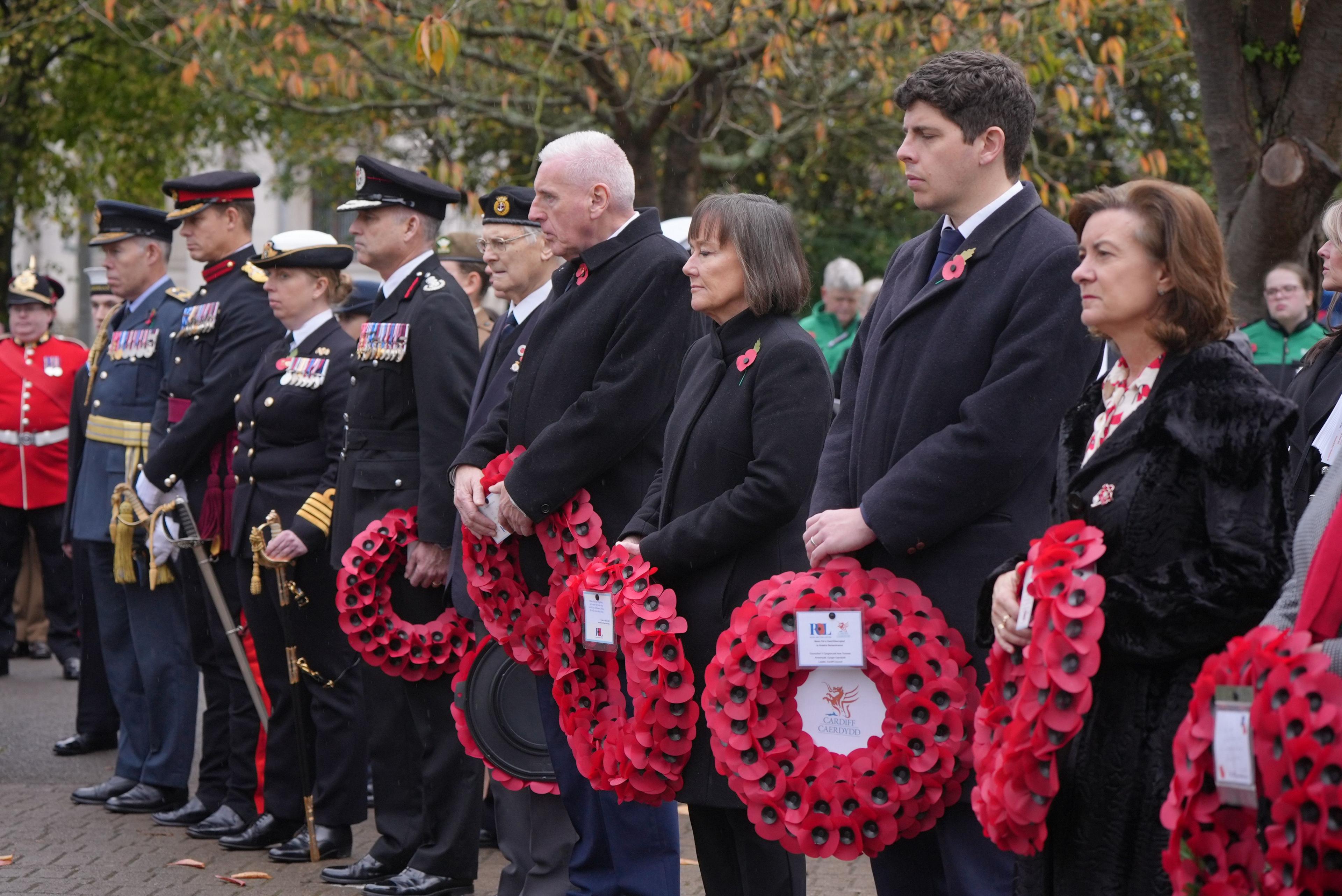Politicians hold wreaths prior to laying them at the memorial