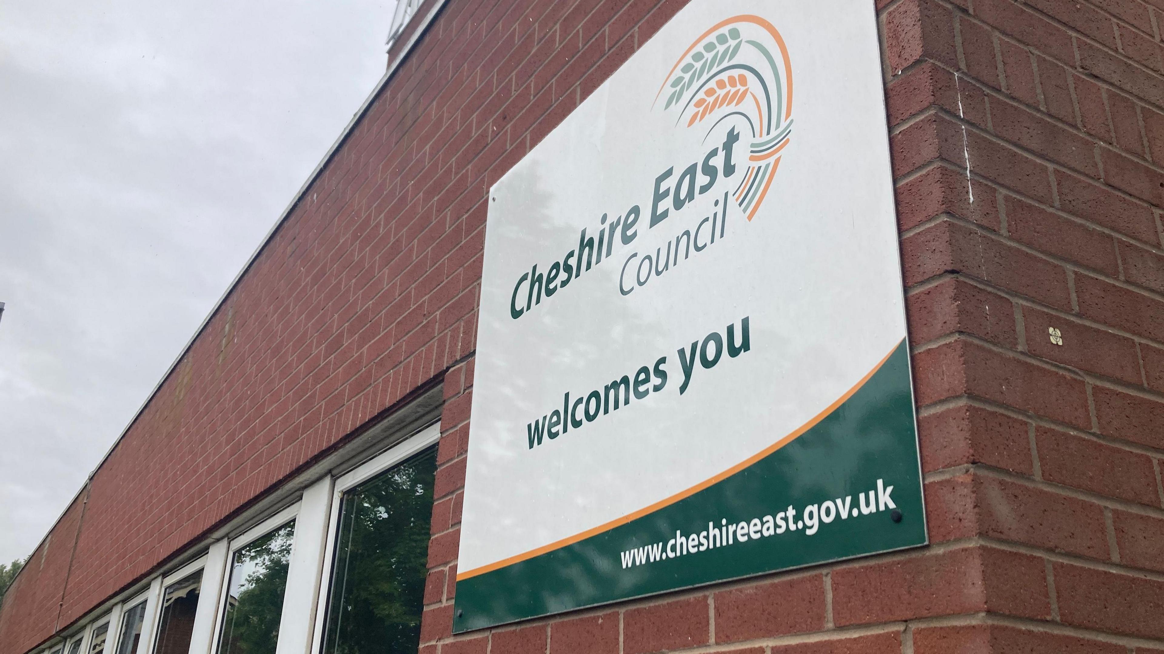 A sign saying Cheshire East Council welcomes you on the side of a building