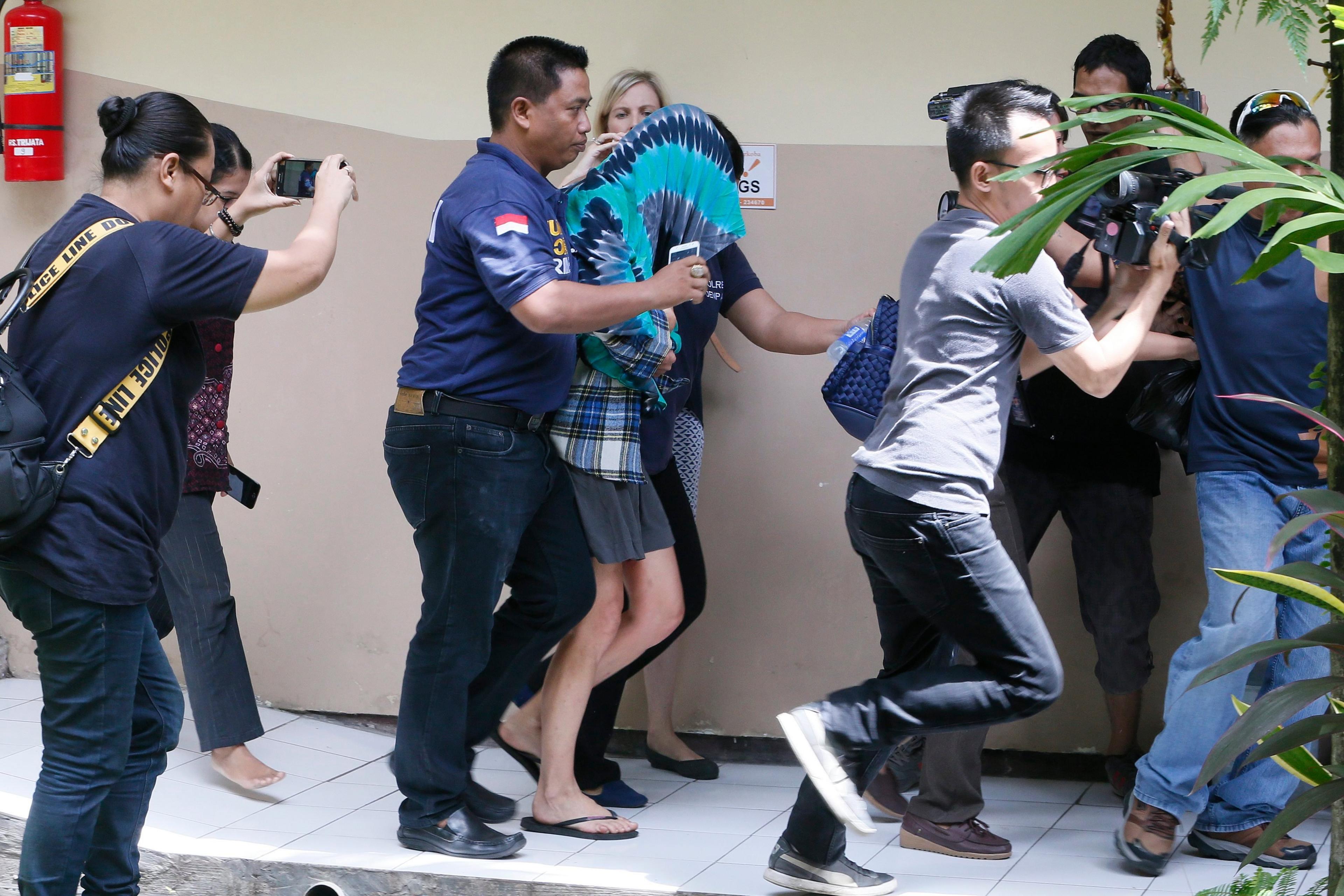 Australian Sara Connor (with hood) is escorted by police officers after her arrest