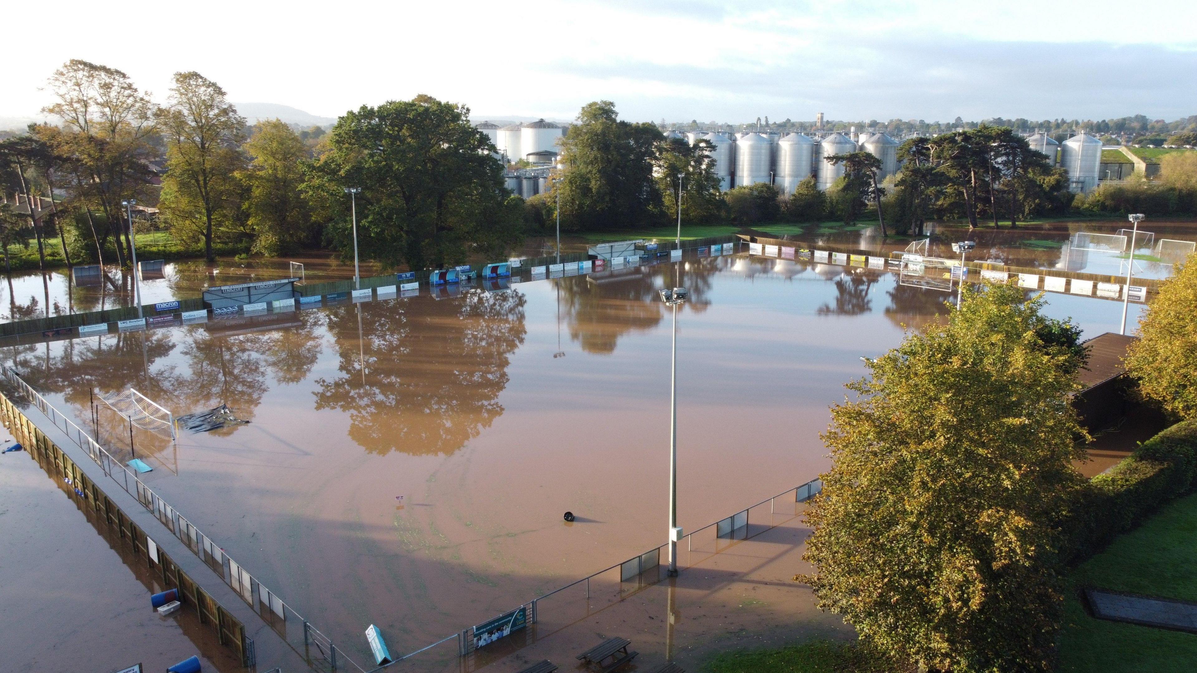 A football pitch flooded with brown flood water