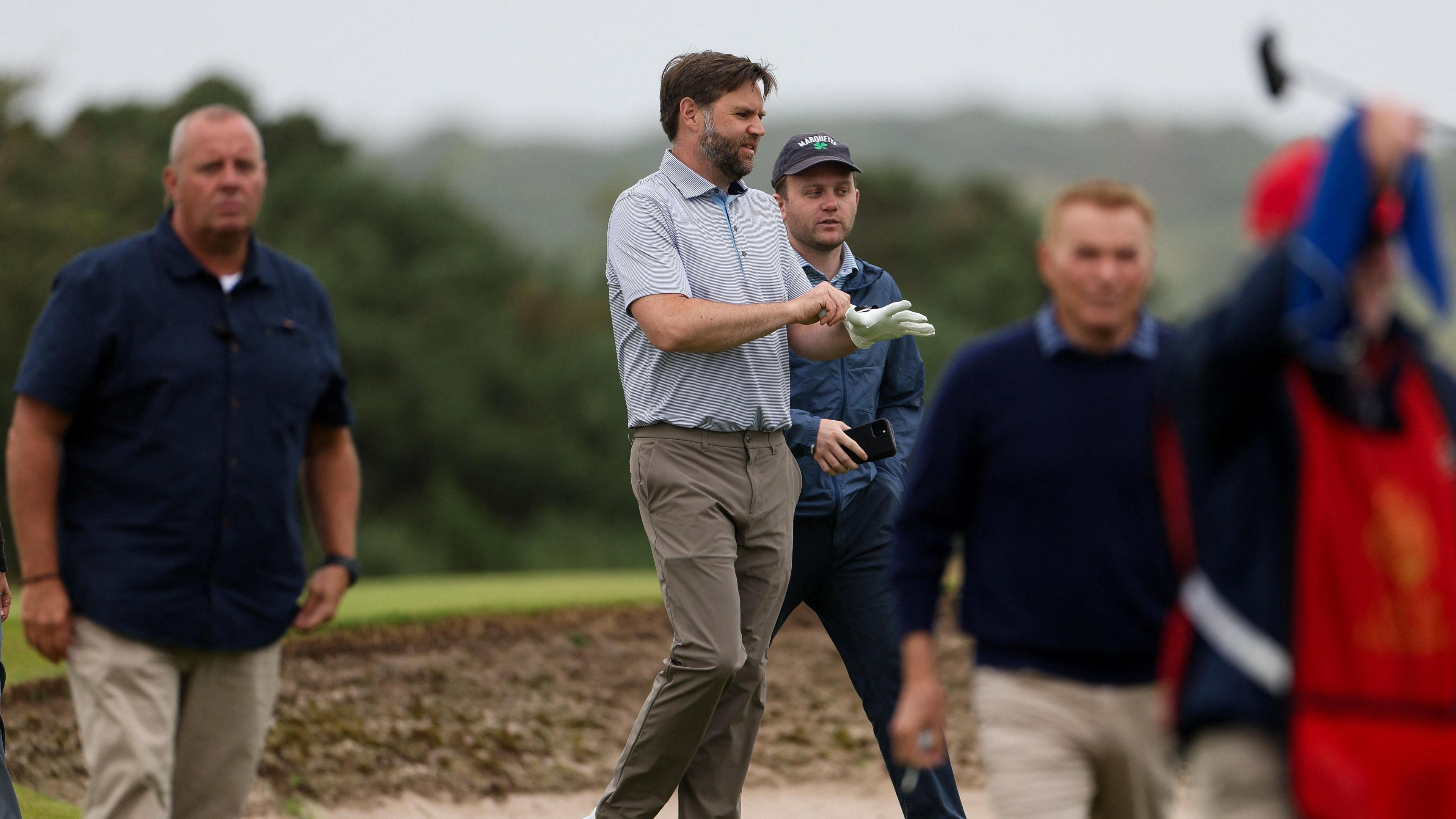 Vance and several guests walked round the course. They are standing in a bunker.
