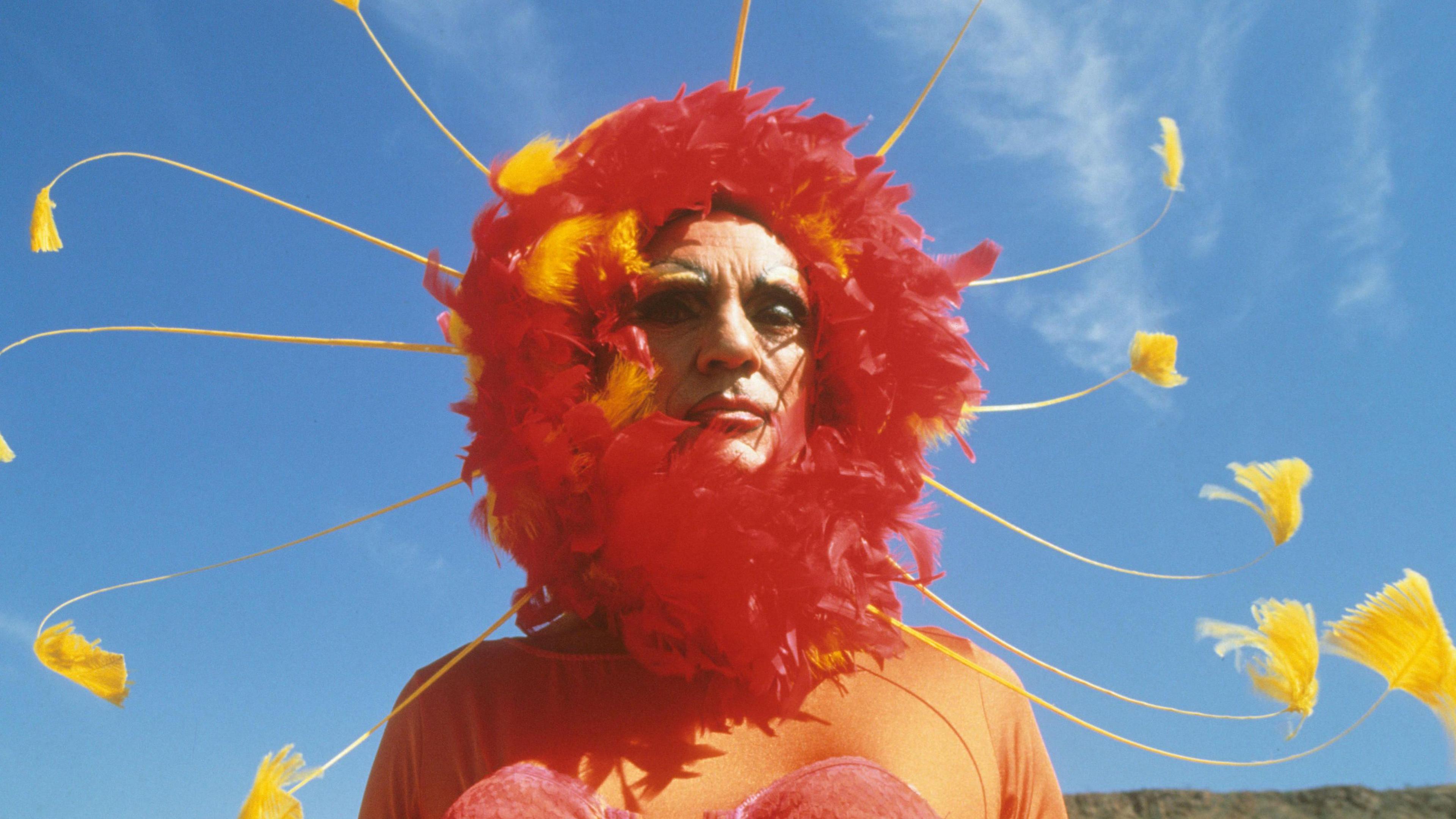 Stamp is wearing a flamboyant red head dress in The Adventures of Priscilla, Queen of the Desert in 1994