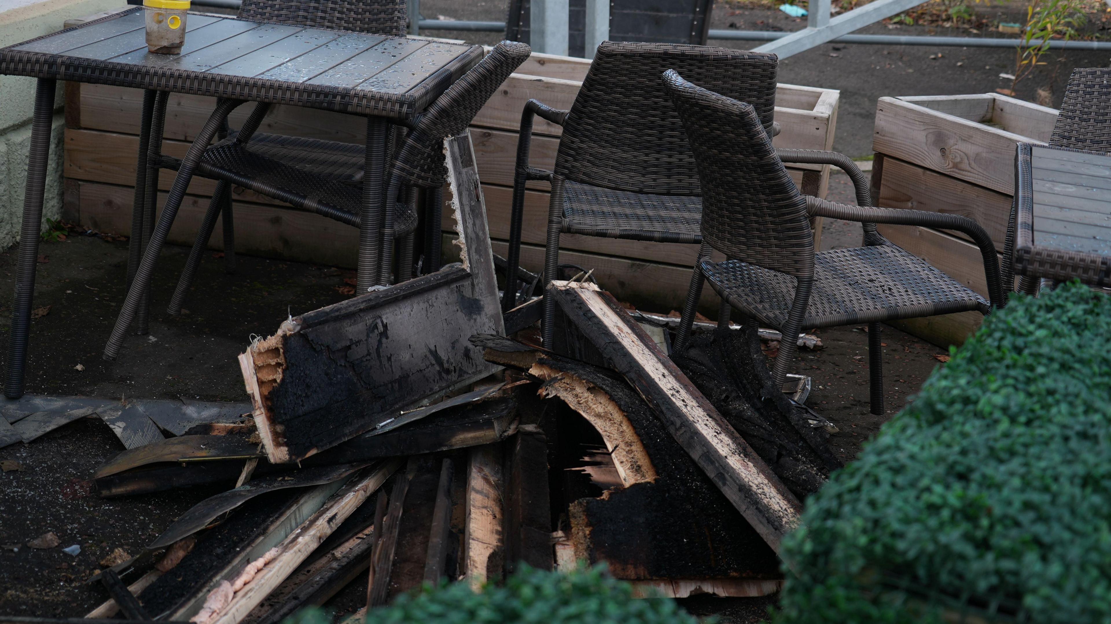 Damaged chairs and tables outside a restaurant. Some have been blackened by fire damage.