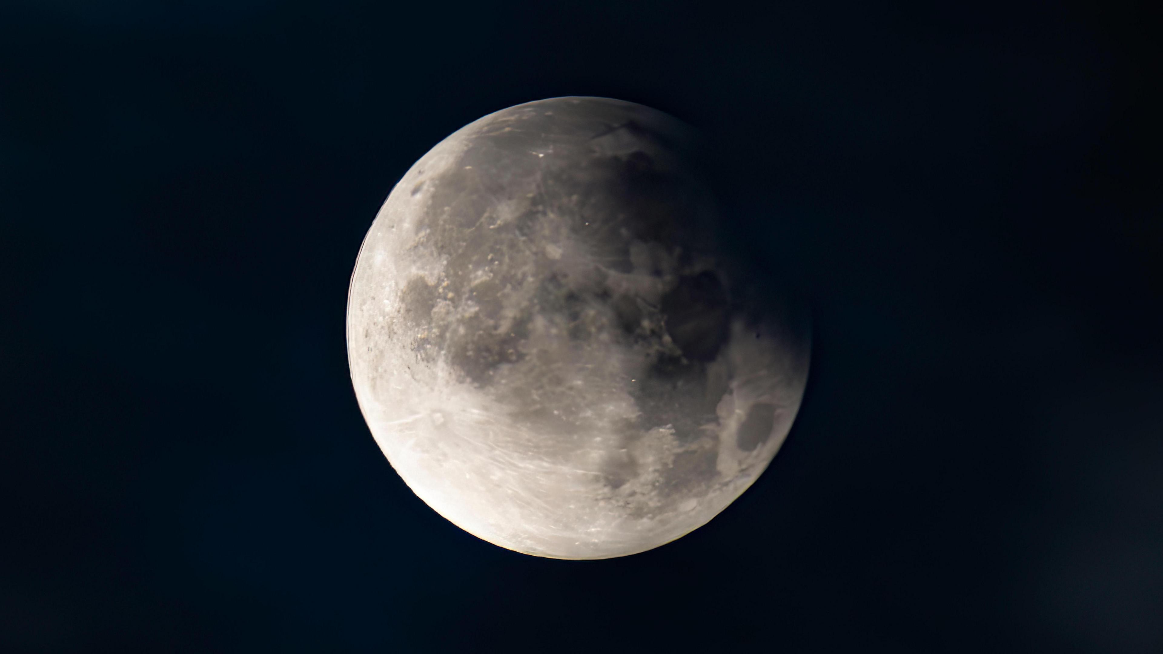 A white, cratered moon in a black night sky.