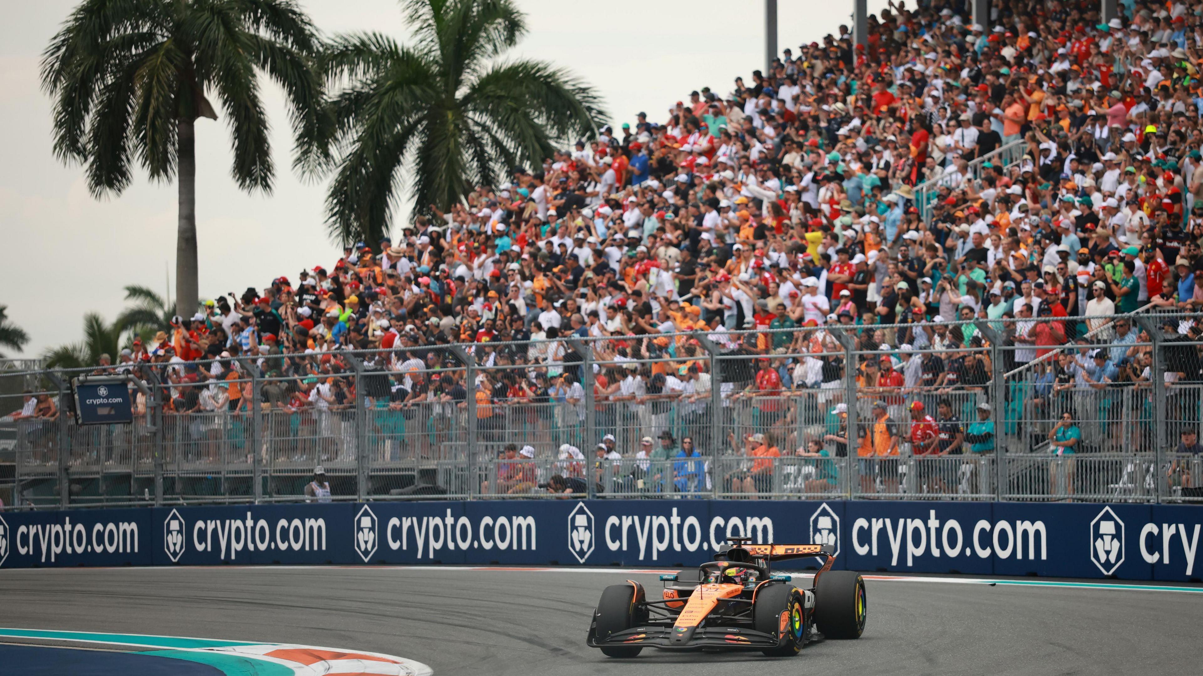 McLaren's Oscar Piastri turns into a right-hand corner during the 2025 Miami Grand Prix. A packed grandstand and two palm trees are in the background
