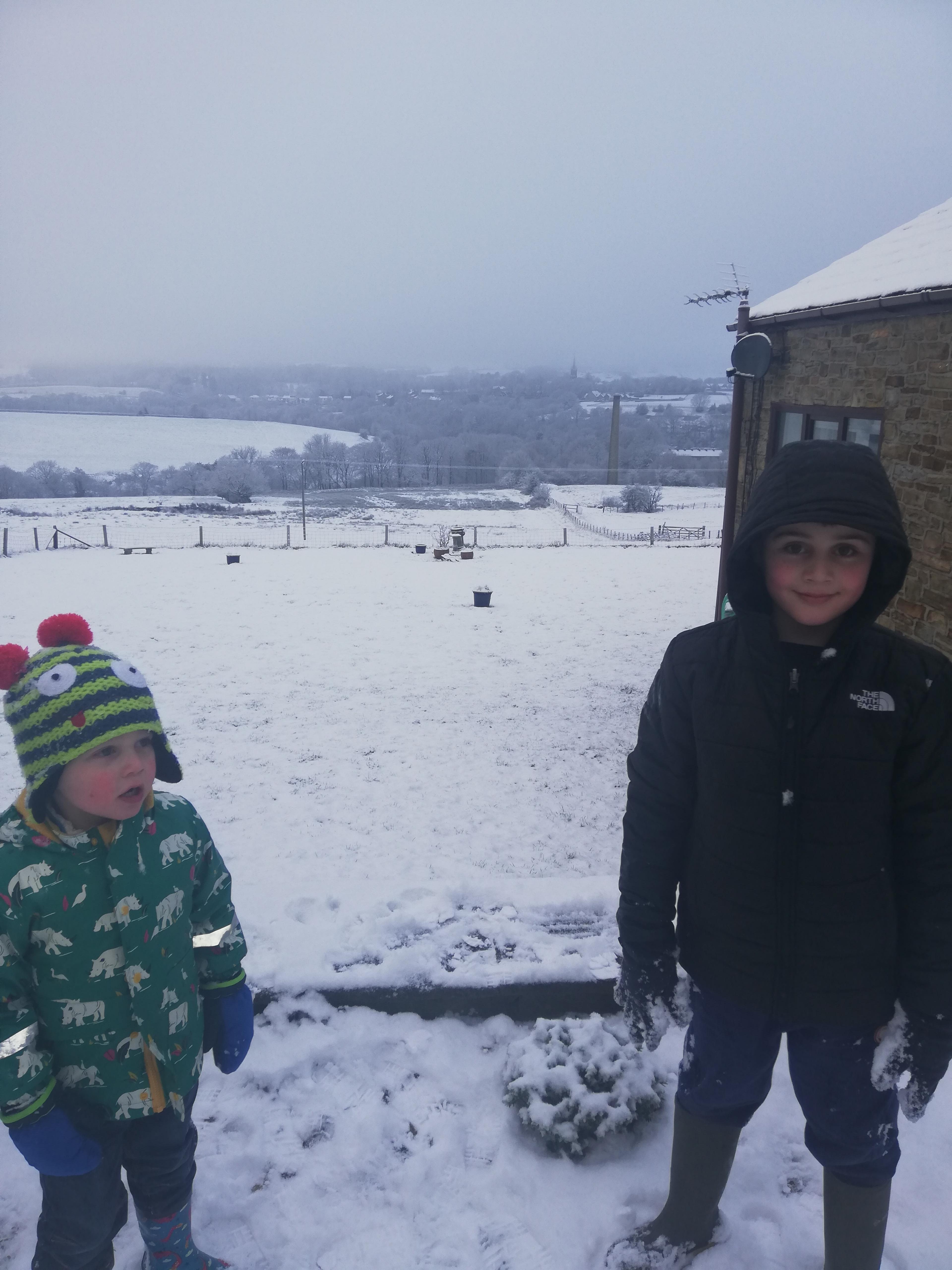 2 boys stand in snowy garden