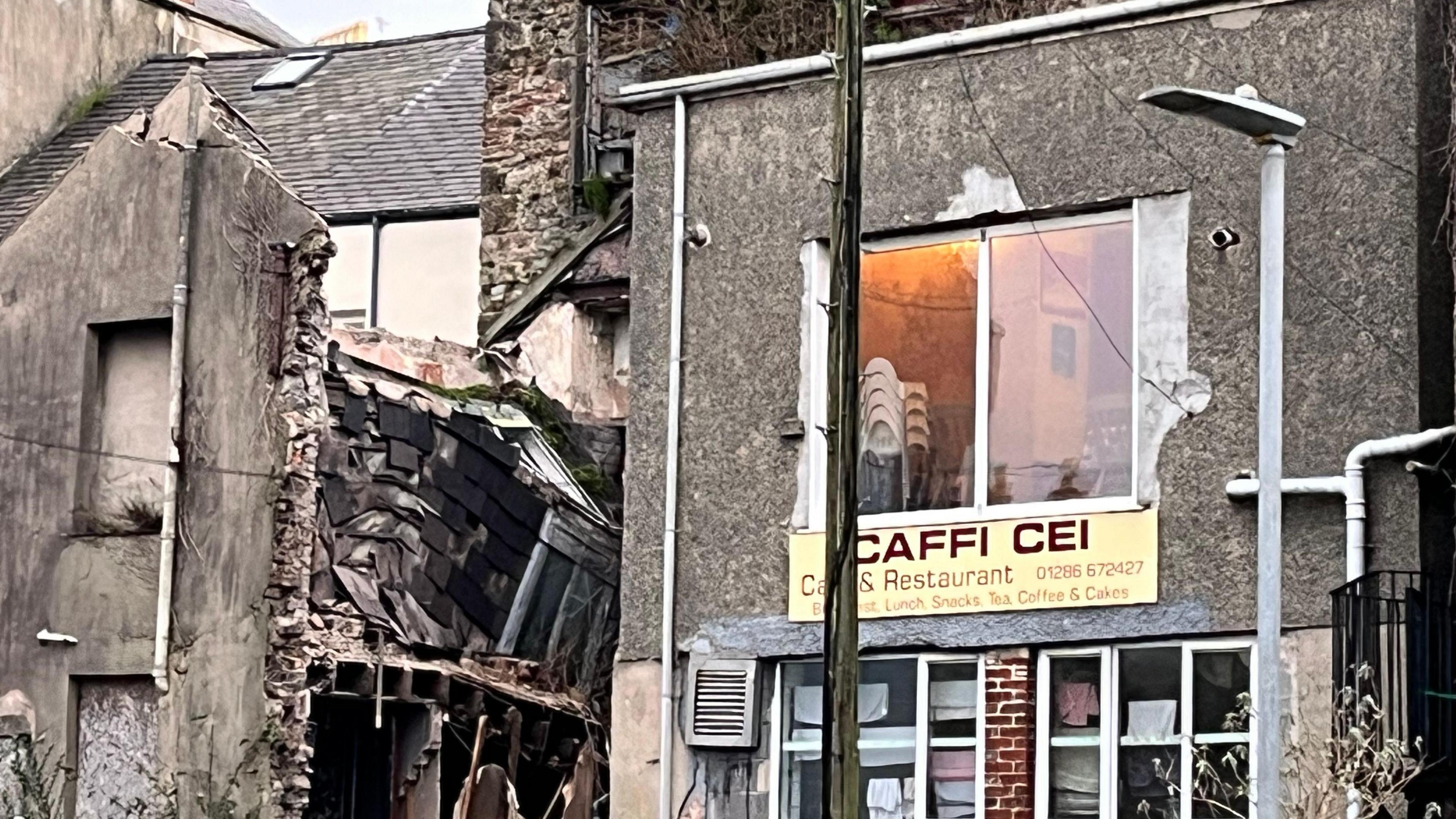 The collapsed building, the inside is visible, bricks and debris lay around. 