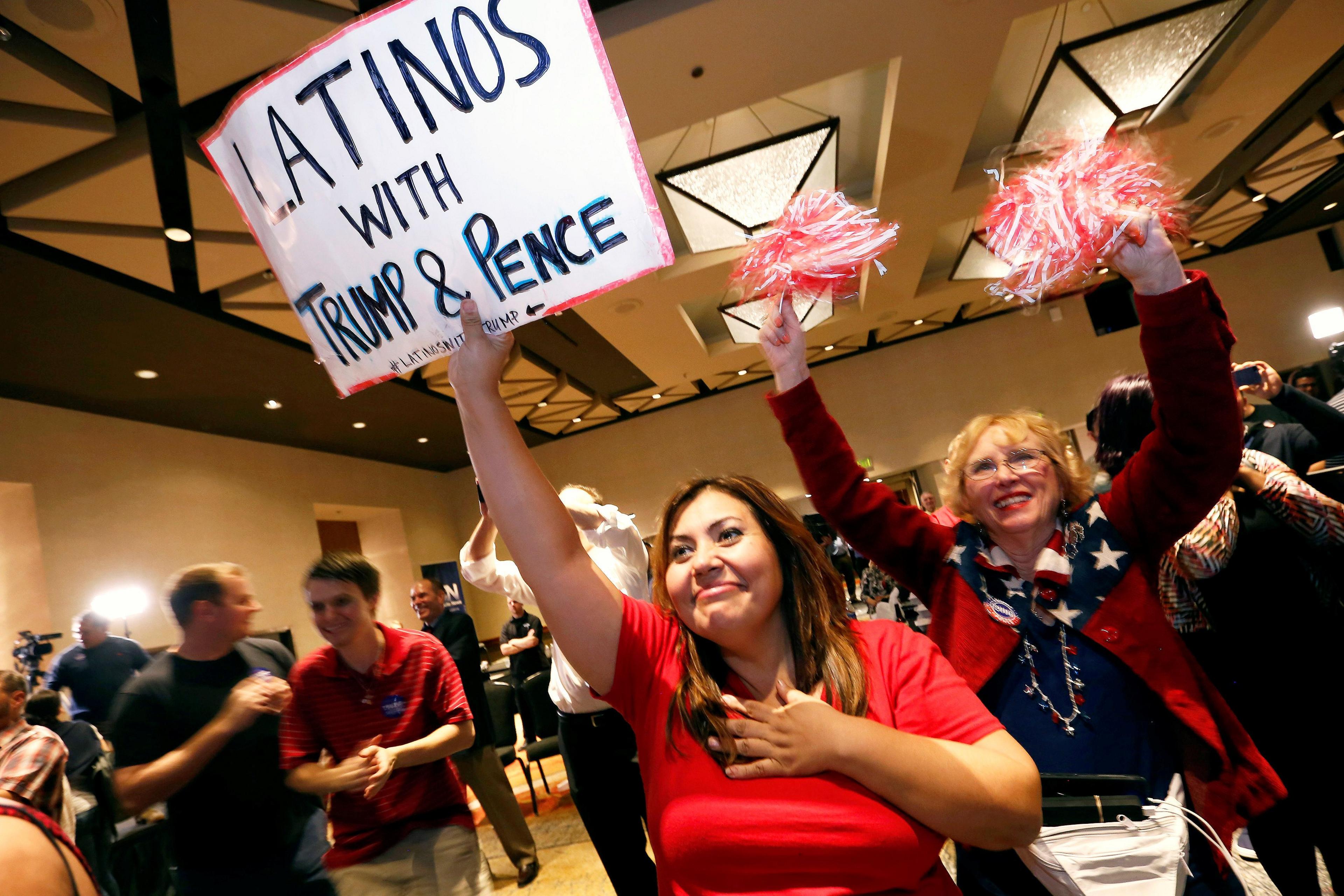 A woman holds up a "Latinos with Trump & Pence" sign