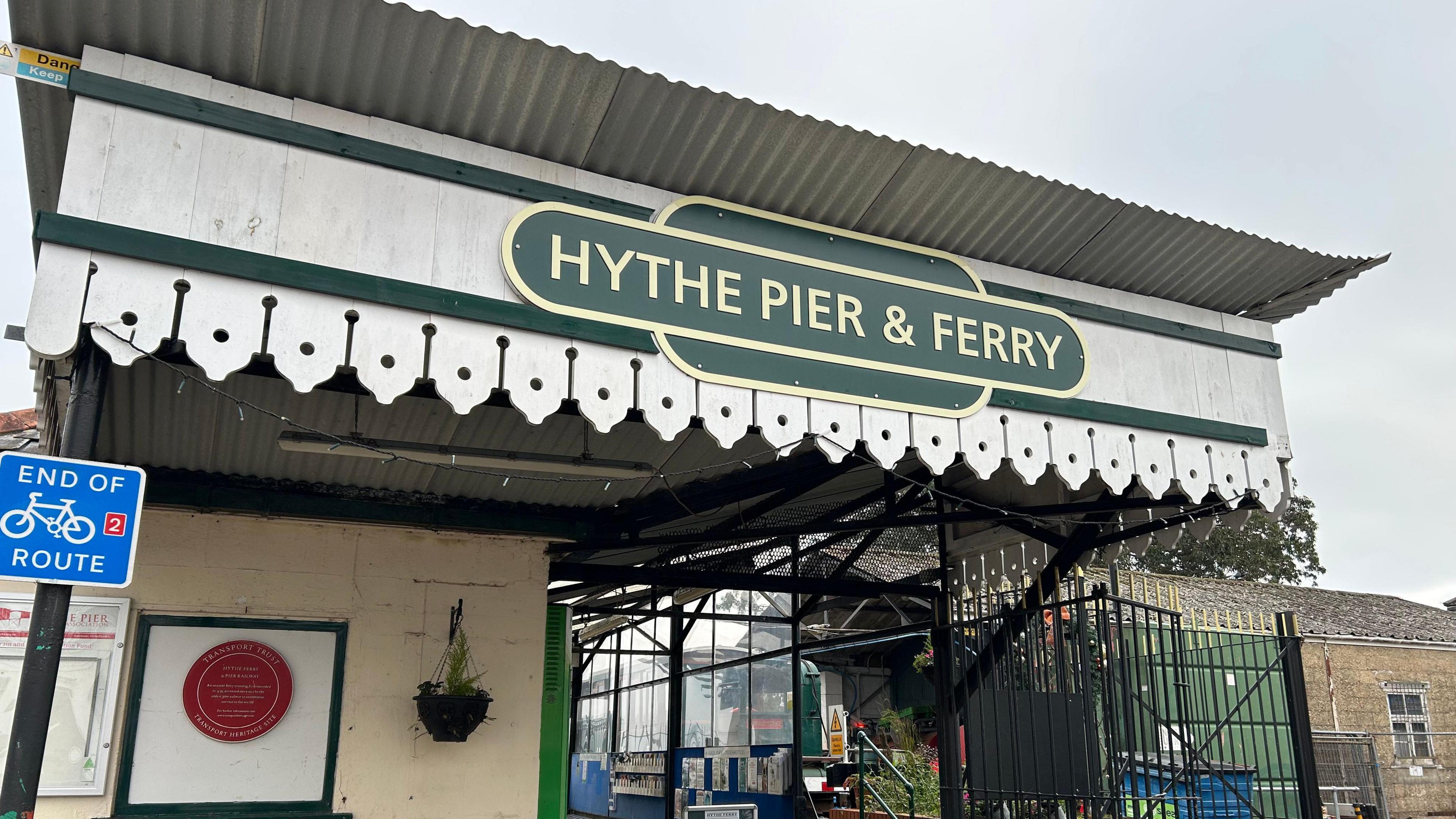 The entrance to Hythe pier including red heritage plaque. The ticket office is on the left hand side.