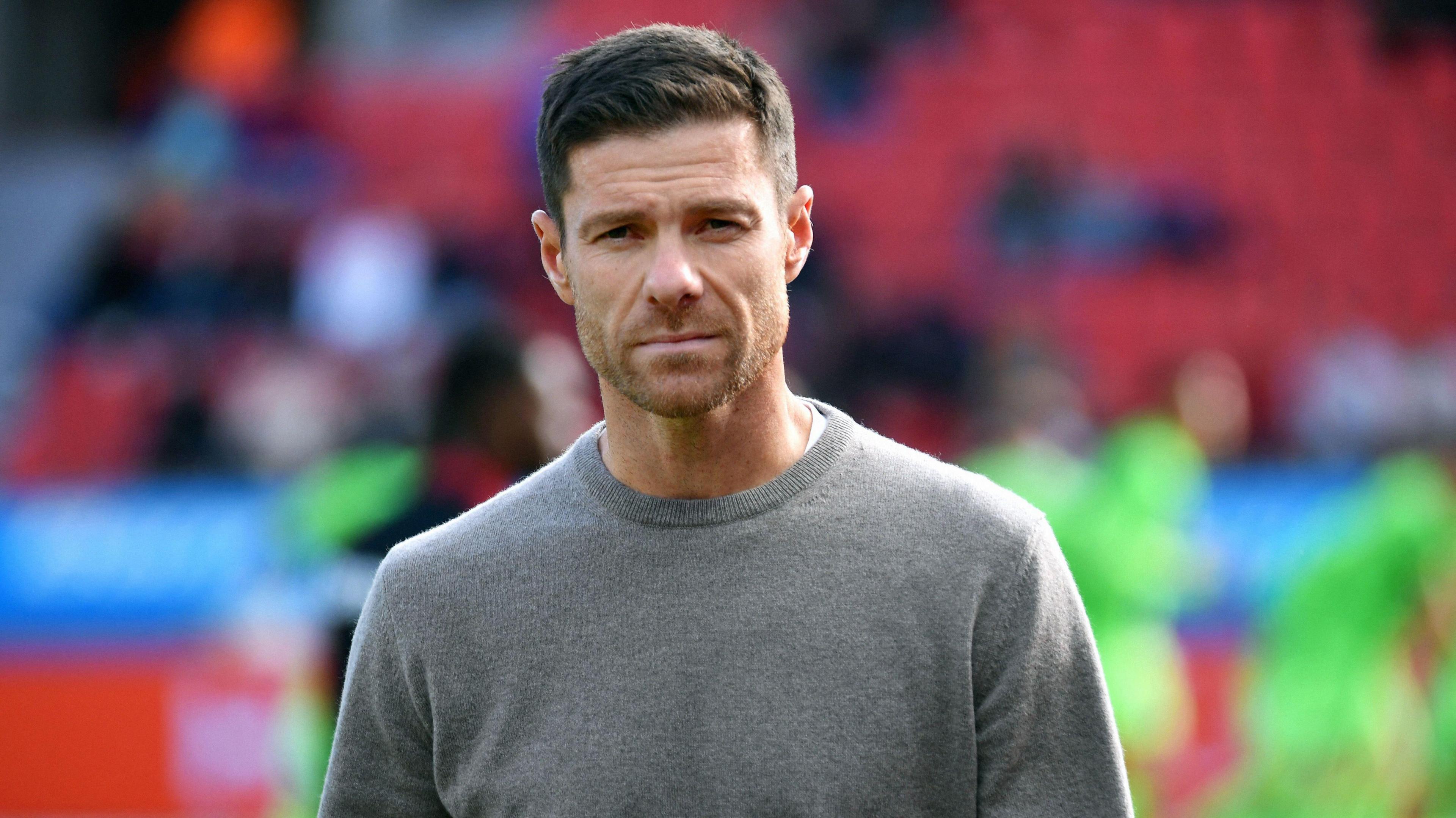 Xavi Alonso wearing a grey jumper staring into the camera while leaving the field after a game