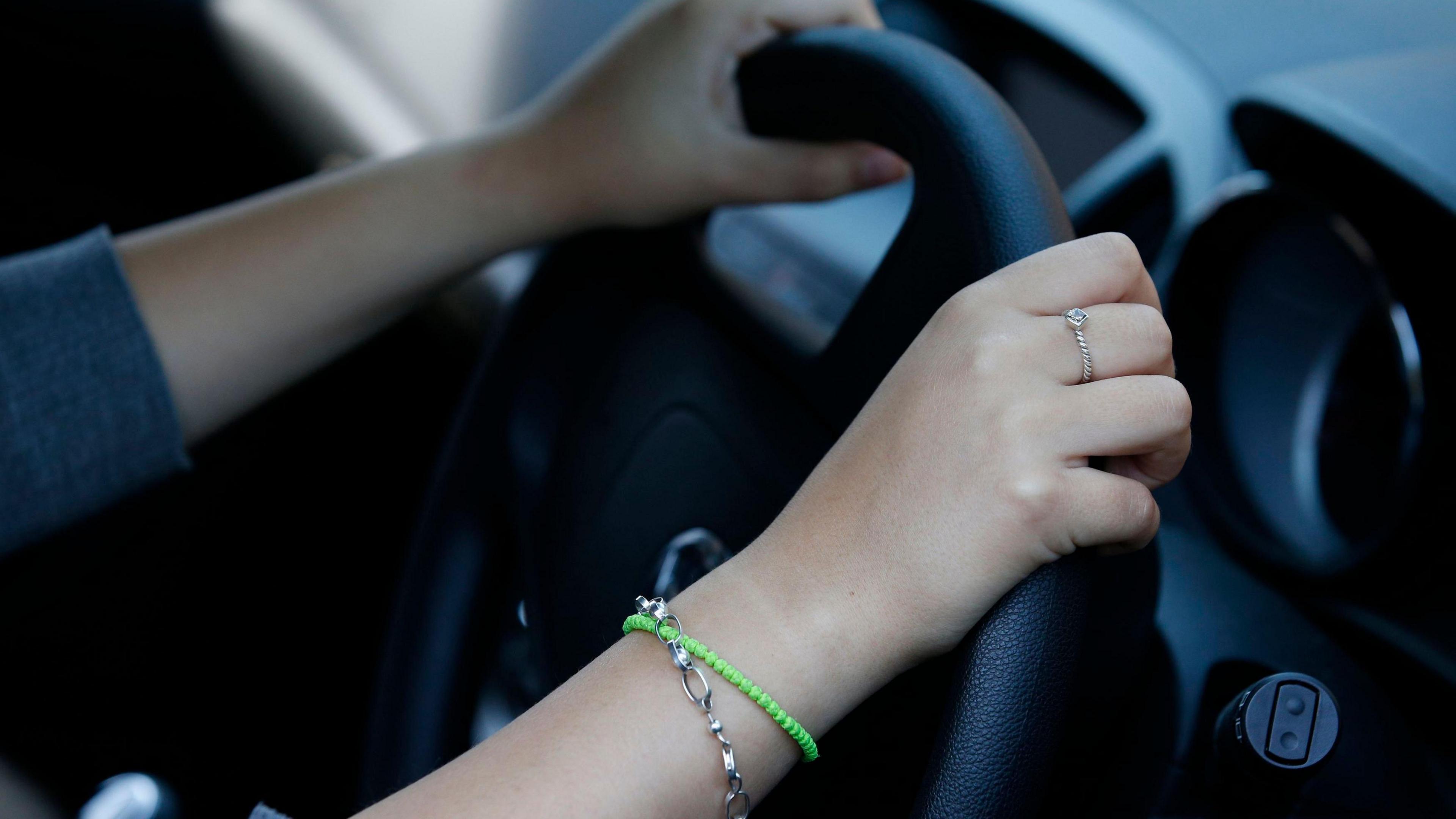 Close up of hands on the steering wheel of a car