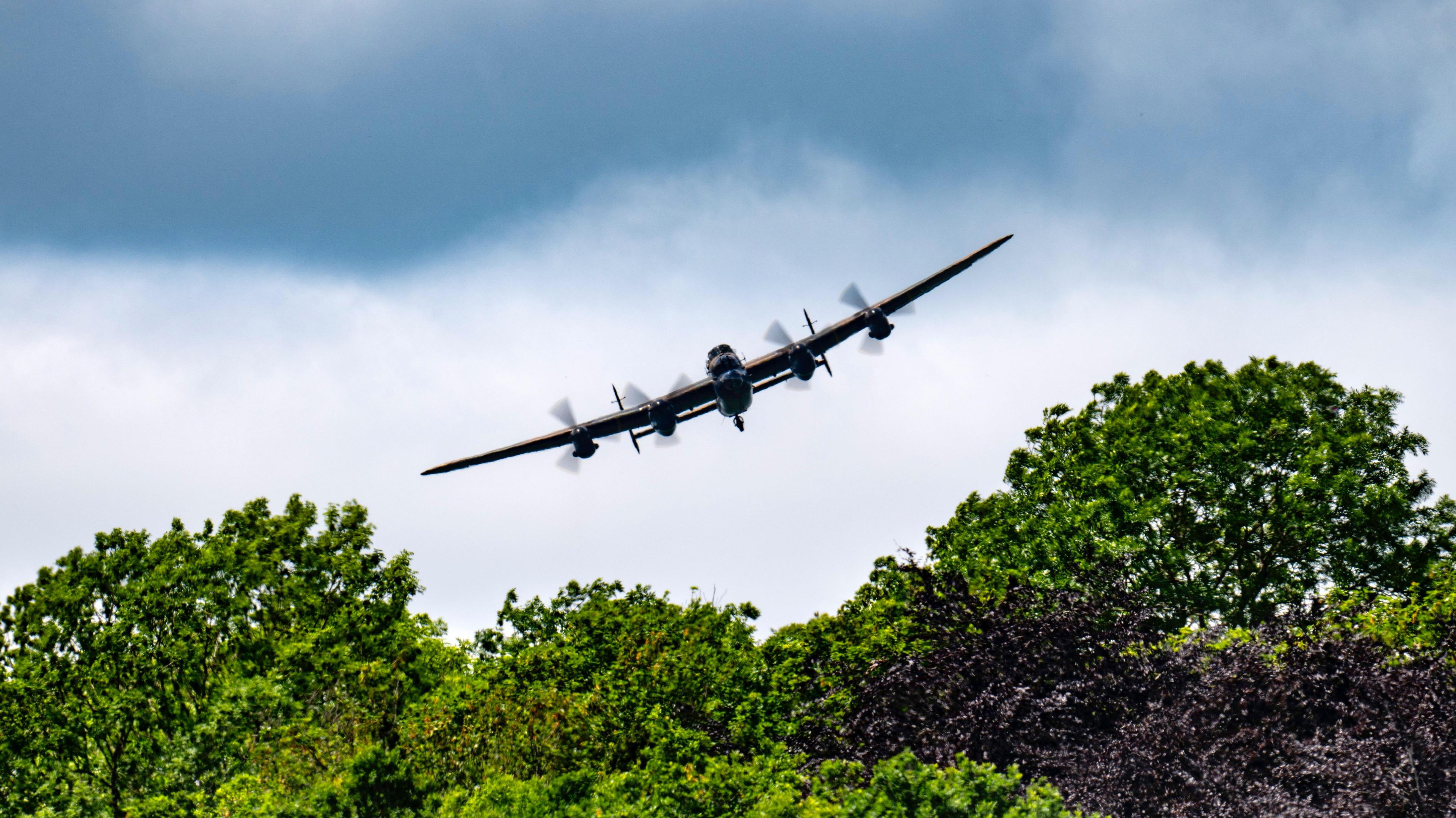 A Lancaster bomber in the skies over trees