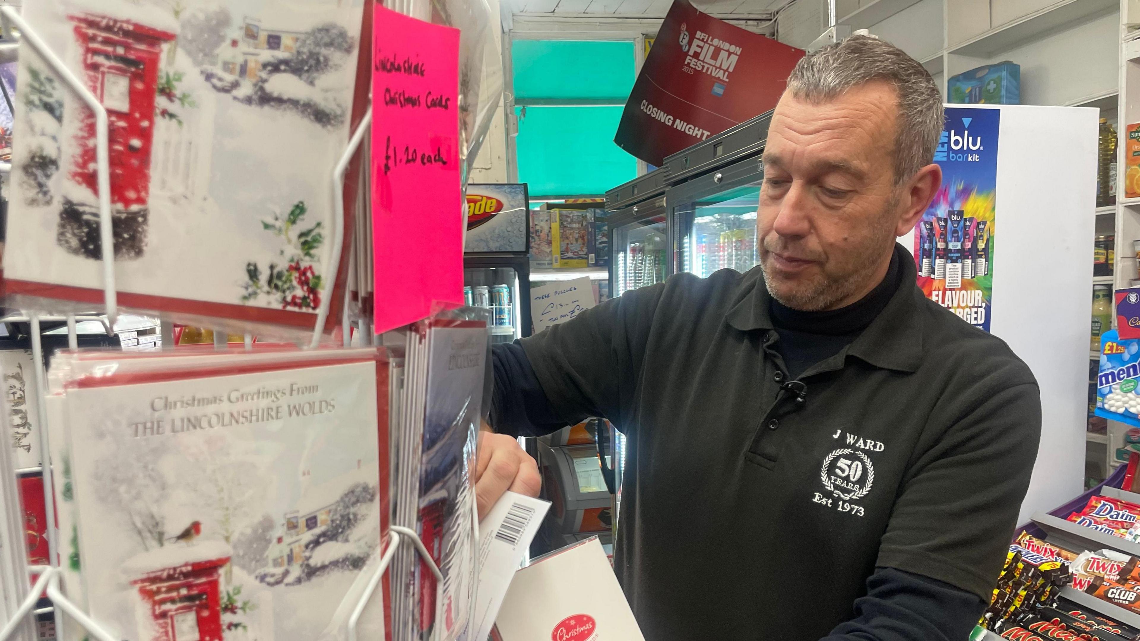 Sub-postmaster David Ward restocks the Lincolnshire Christmas cards on sale at East Barkwith Post Office
