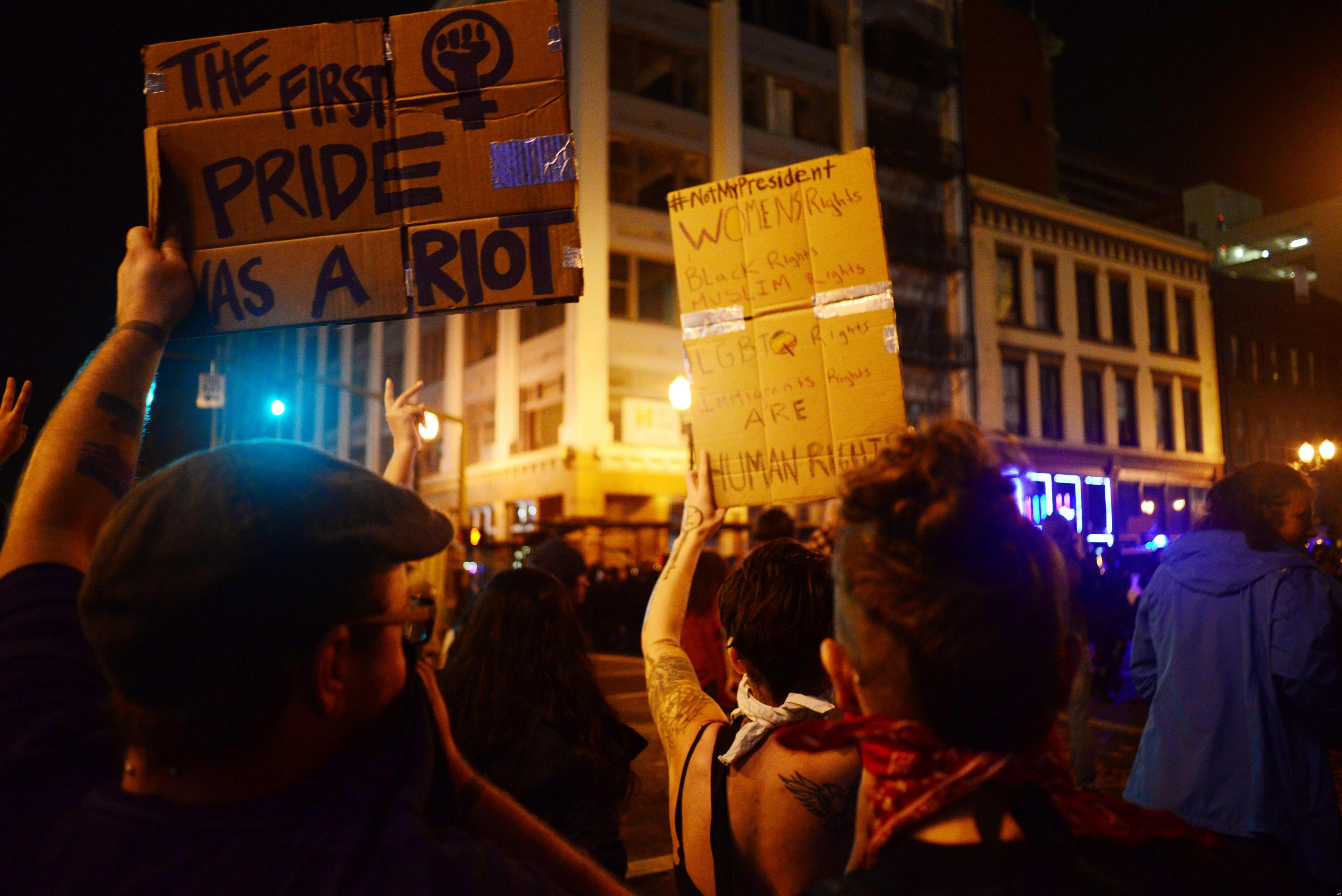 Demonstrators hold up placards during a protest against Donald Trump"s US presidential election victory, at City Hall in Portland on November 11, 2016.