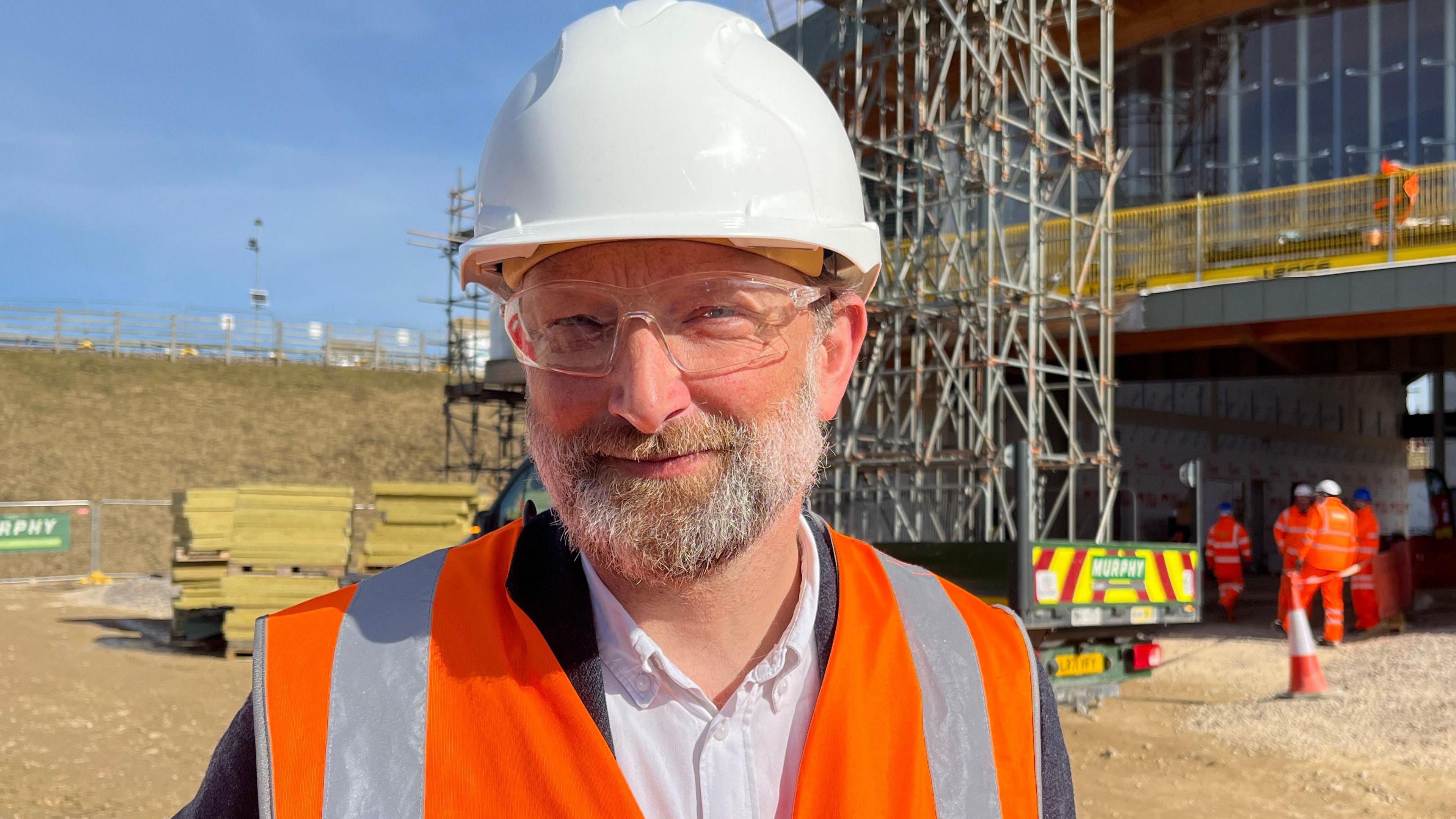 Jan Kroes wearing hi-vis, in the background are some building materials and scaffolding.