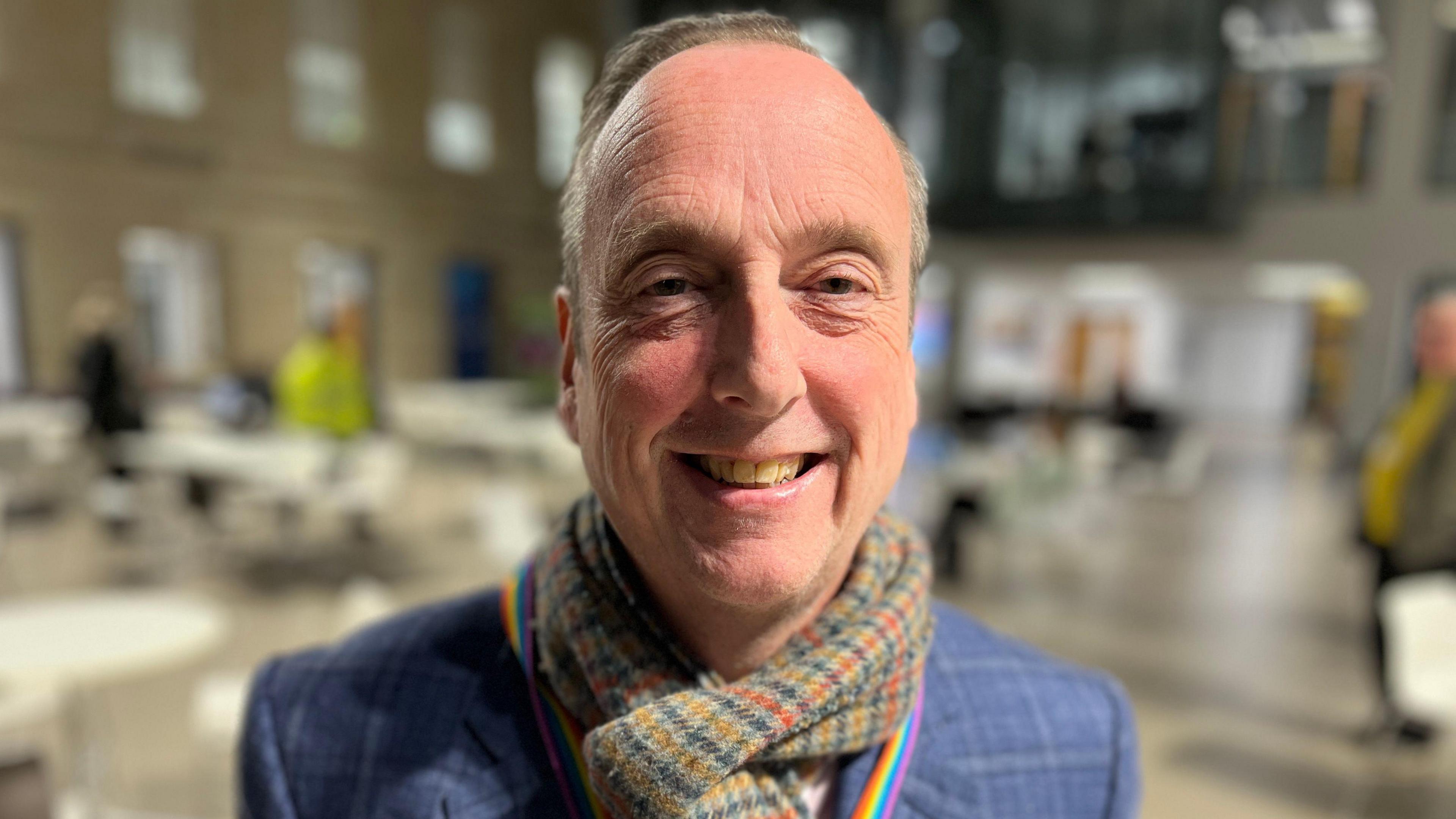 Liberal Democrat leader on Wiltshire Council Ian Thorn smiles at the camera in a blue suit jacket and woolly scarf.