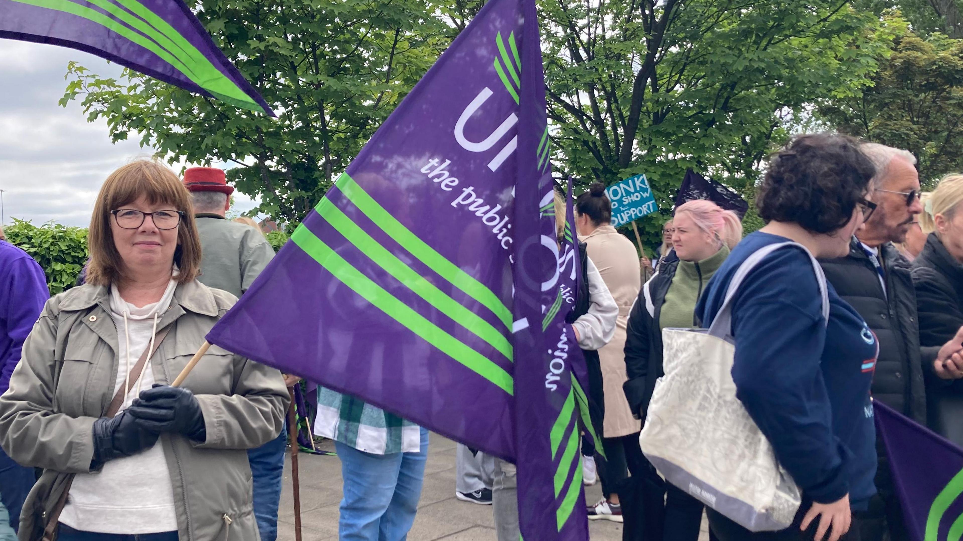 A group of striking healthcare workers holding Unison flags