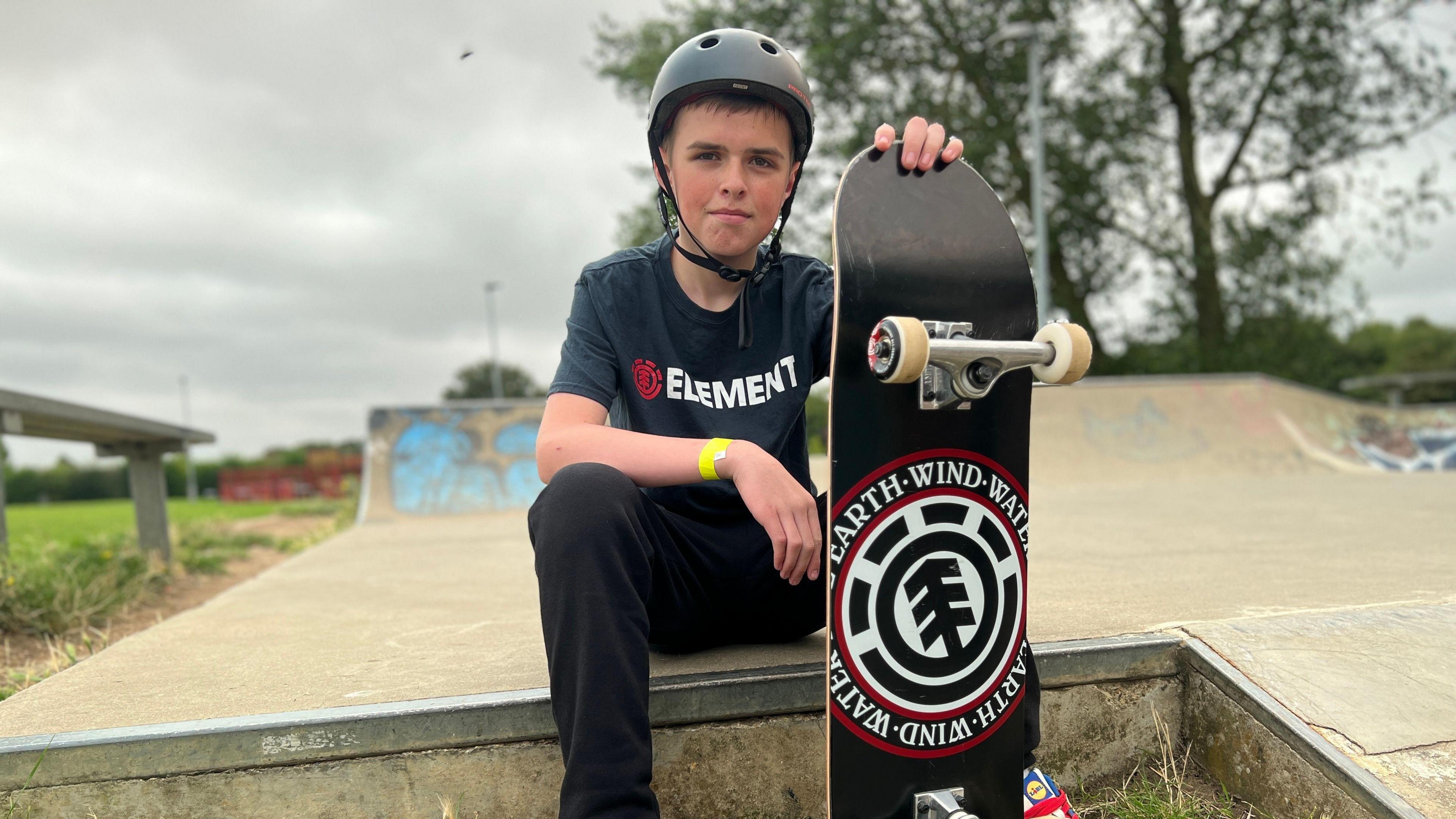 Boy sitting on ramp with skateboard