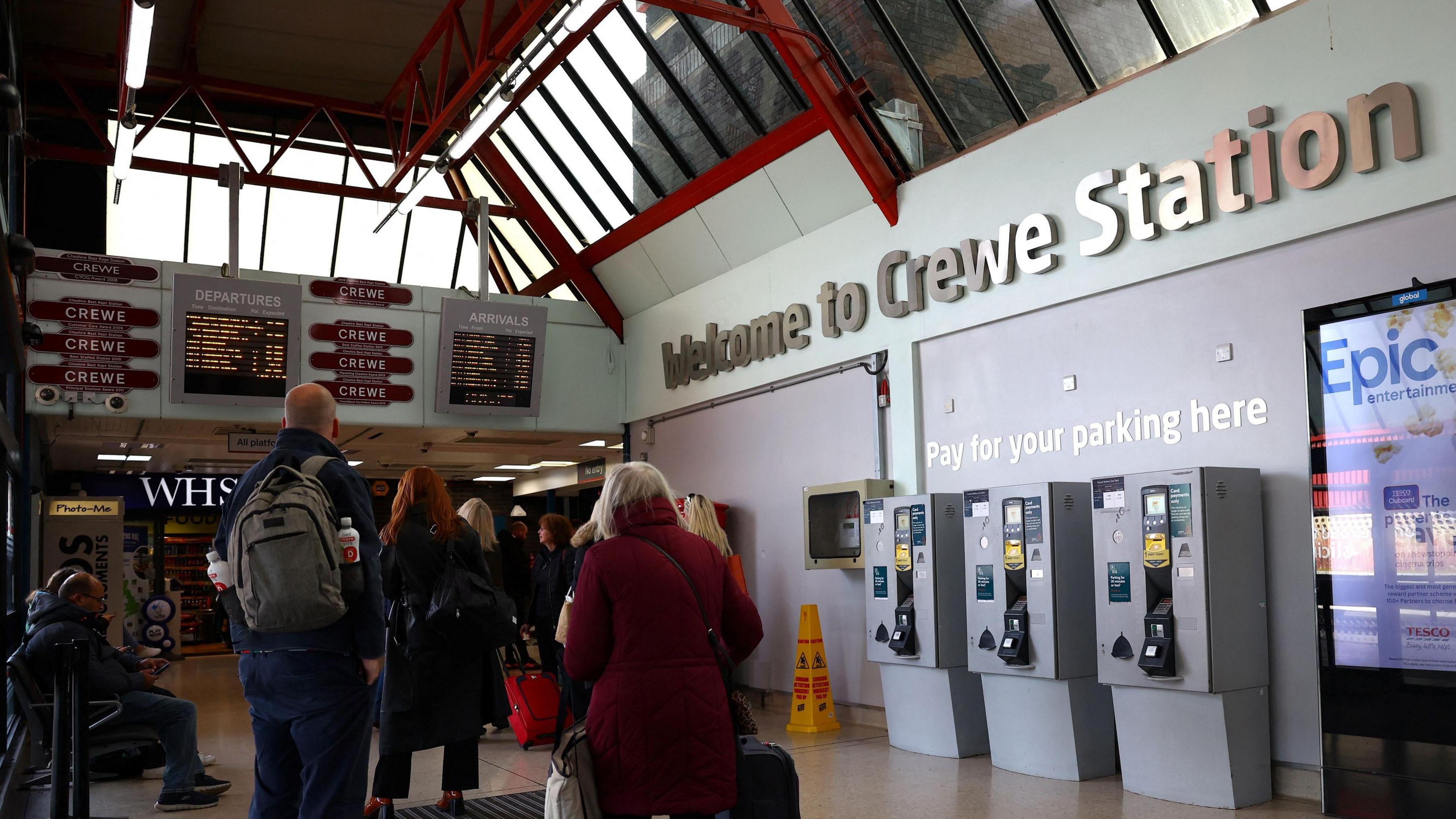 Passengers look at information boards at Crewe Railway Station