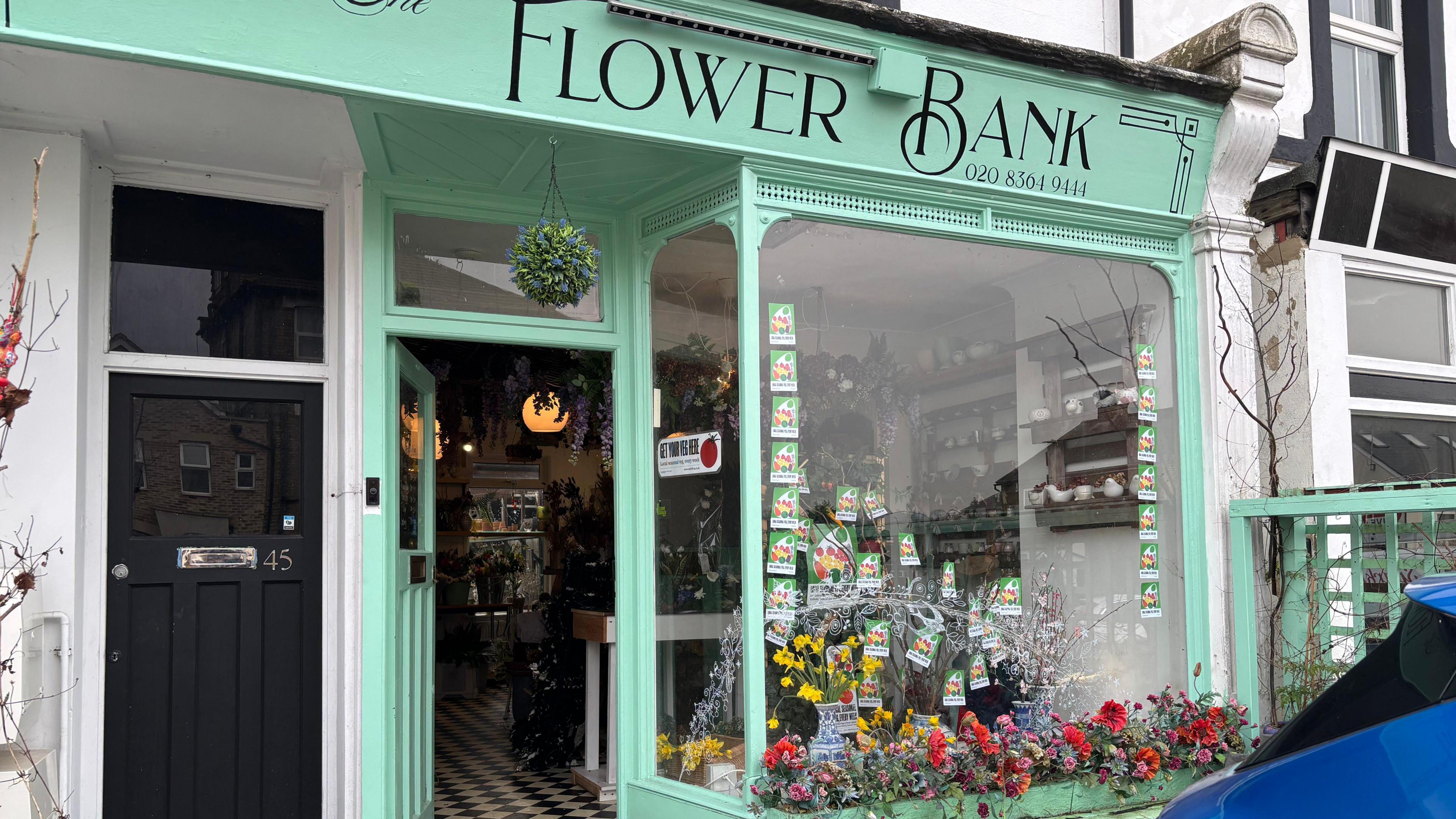 The entrance of the flower bank shop with flowers outside it