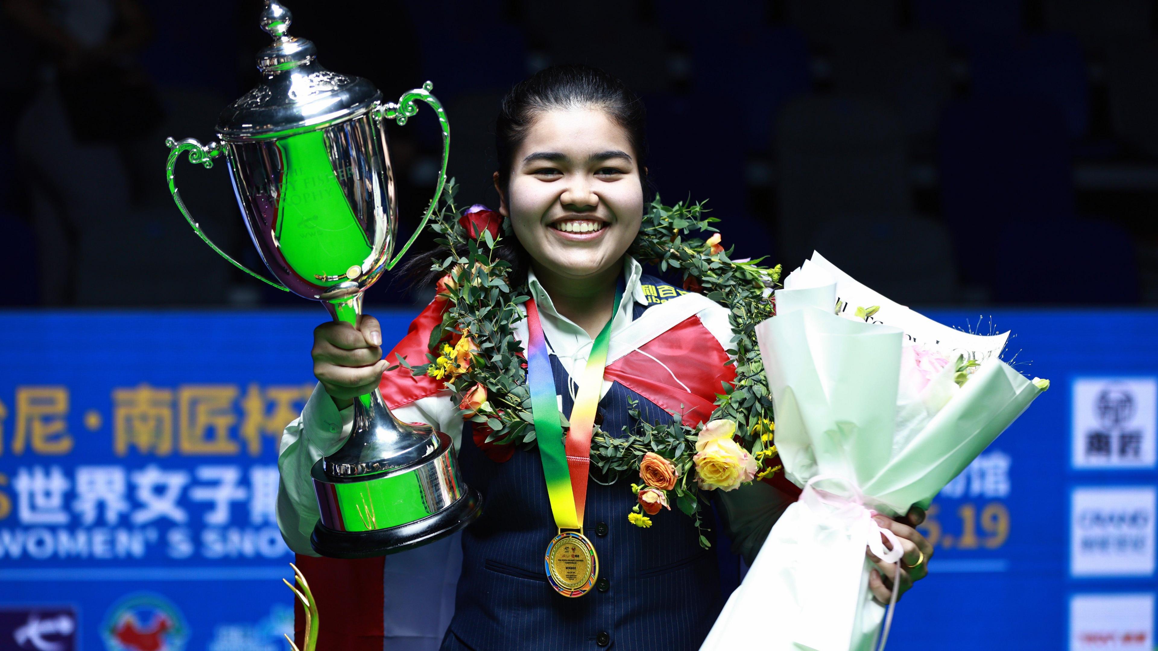 Women's world snooker champion Panchaya Channoi holds the Mandy Fisher Trophy and a bouquet of flowers