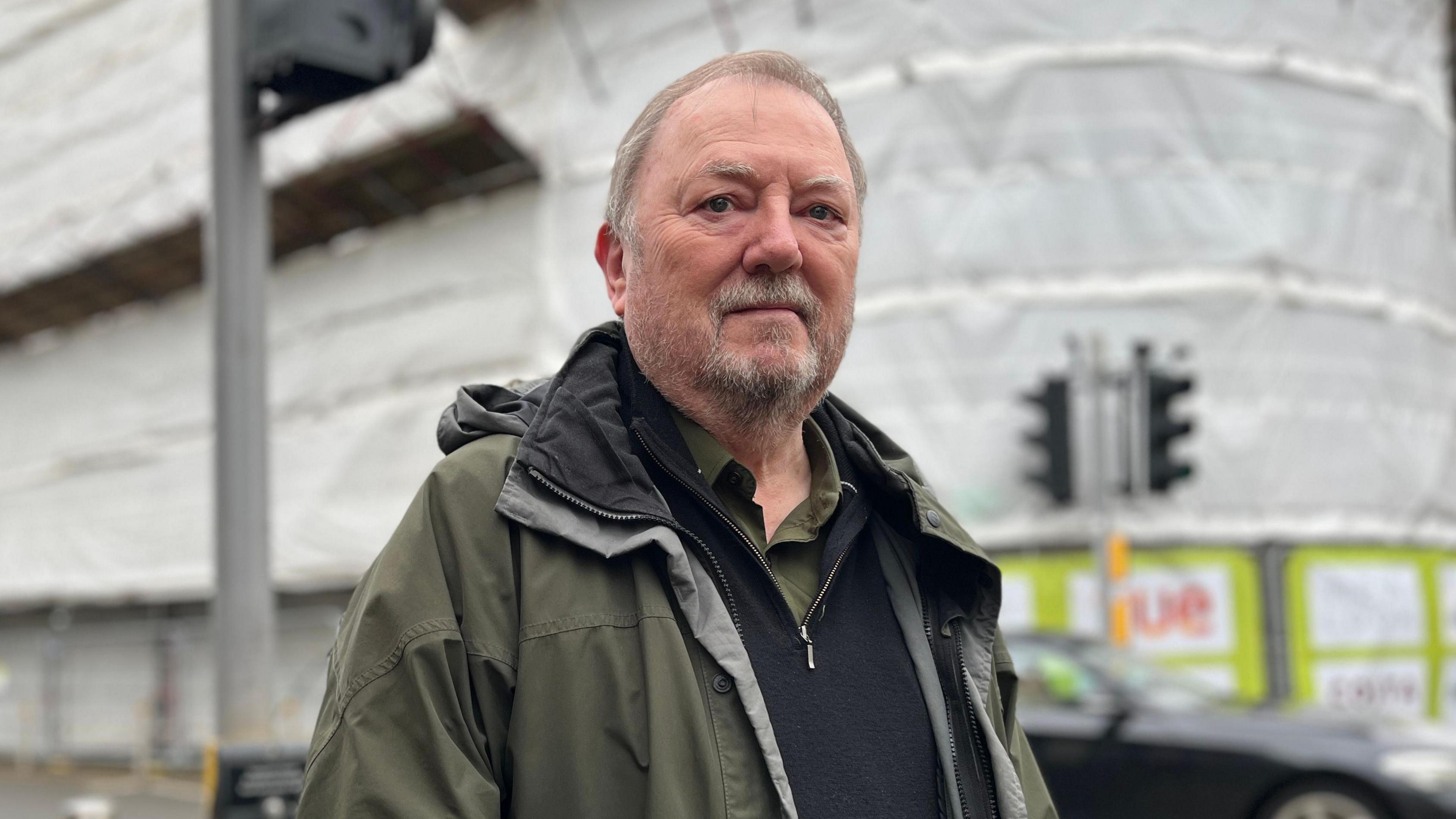 Cynghorydd Alun Lenny y tu allan i'r ganolfan newydd sy'n cael ei datblygu yng Nghaerfyrddin