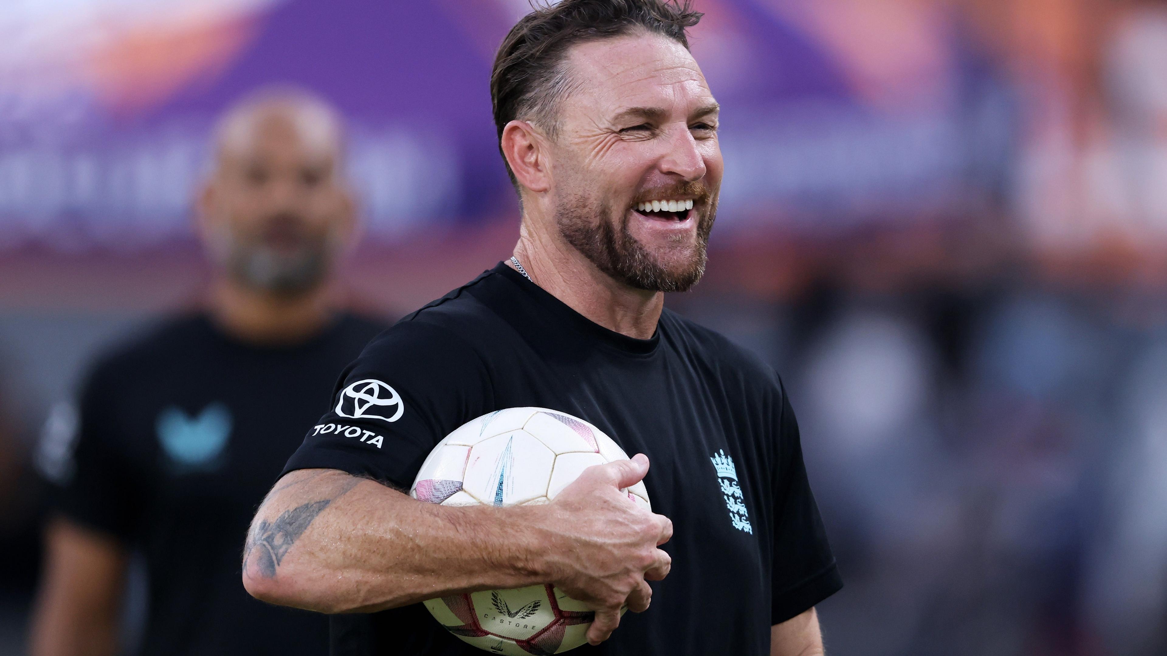 Brendon McCullum smiles with a football under his arm