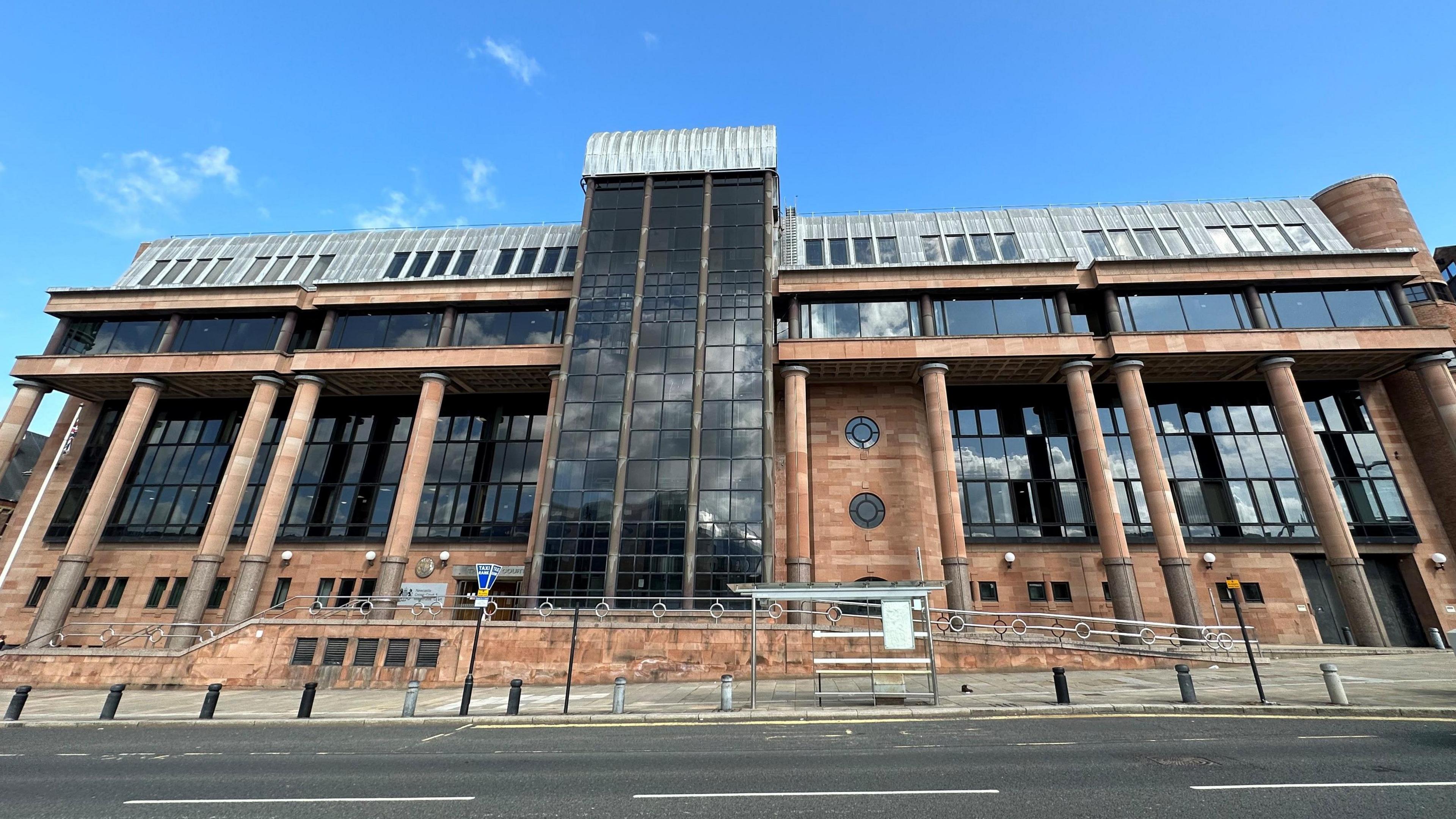 A large red brick court building with large windows.