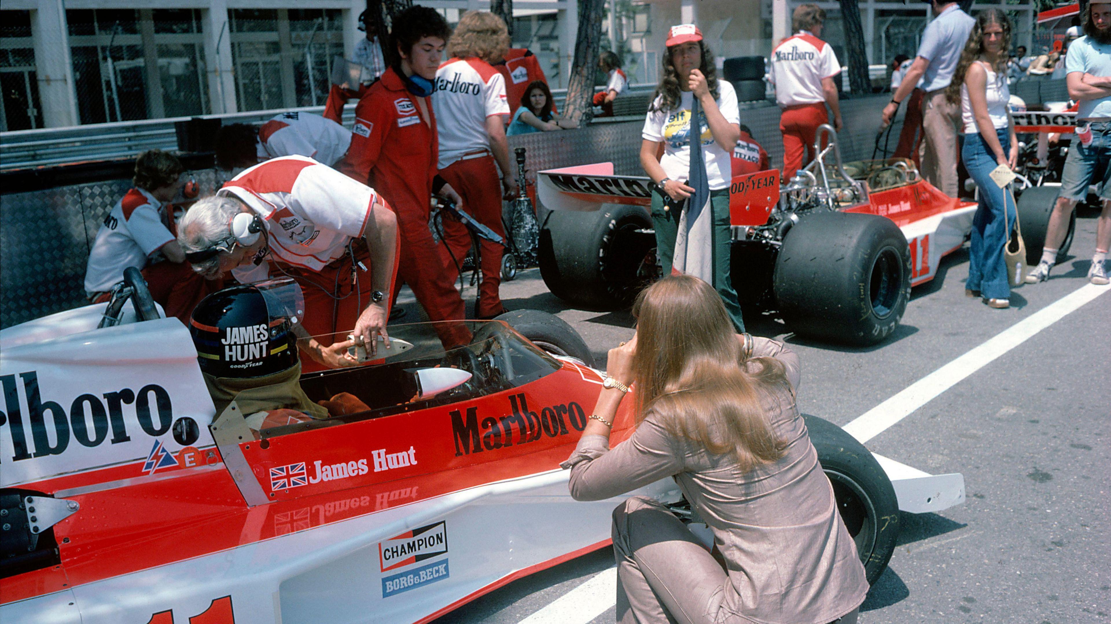 Helen Stewart, the wife of three-time world champion Sir Jackie Stewart, crouches to take a picture of fellow Briton James Hunt in his McLaren in 1976