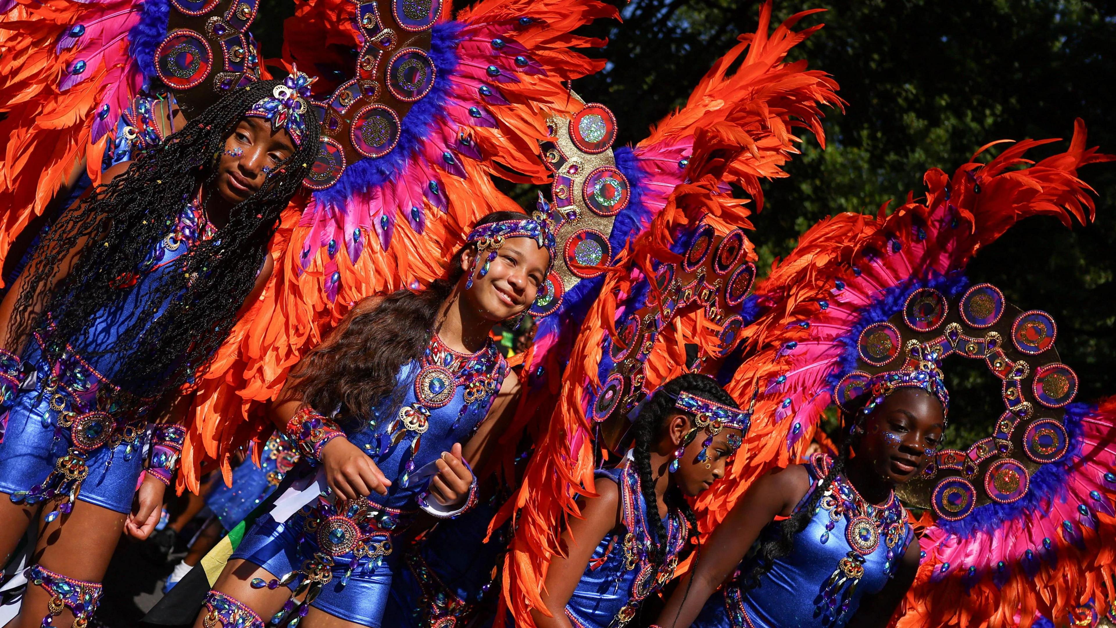 Children in blue, pink and orange feathered and jeweled costumes take part in the parade.