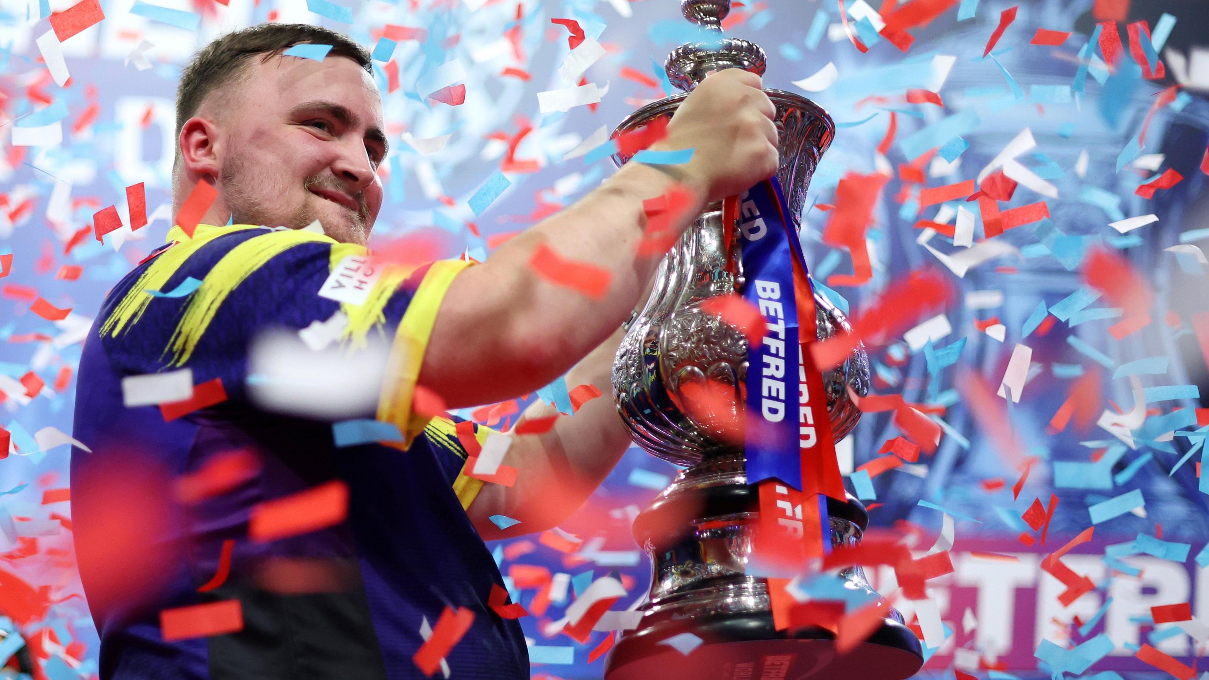 Luke Littler raises the Phil Taylor Trophy