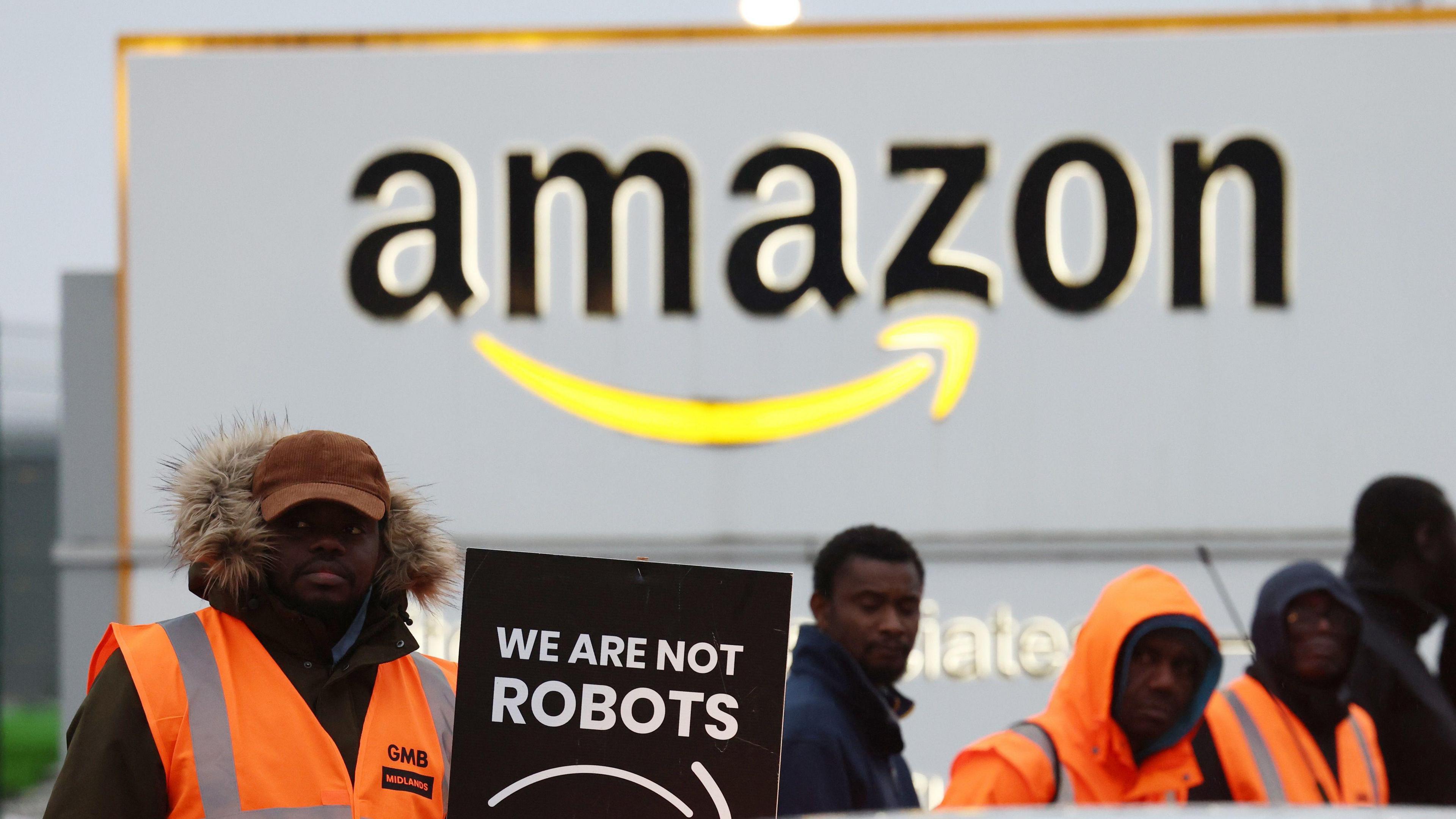 Amazon workers holding a placard reading 'we are not robots' on a picket line during a strike at the Amazon Coventry site.