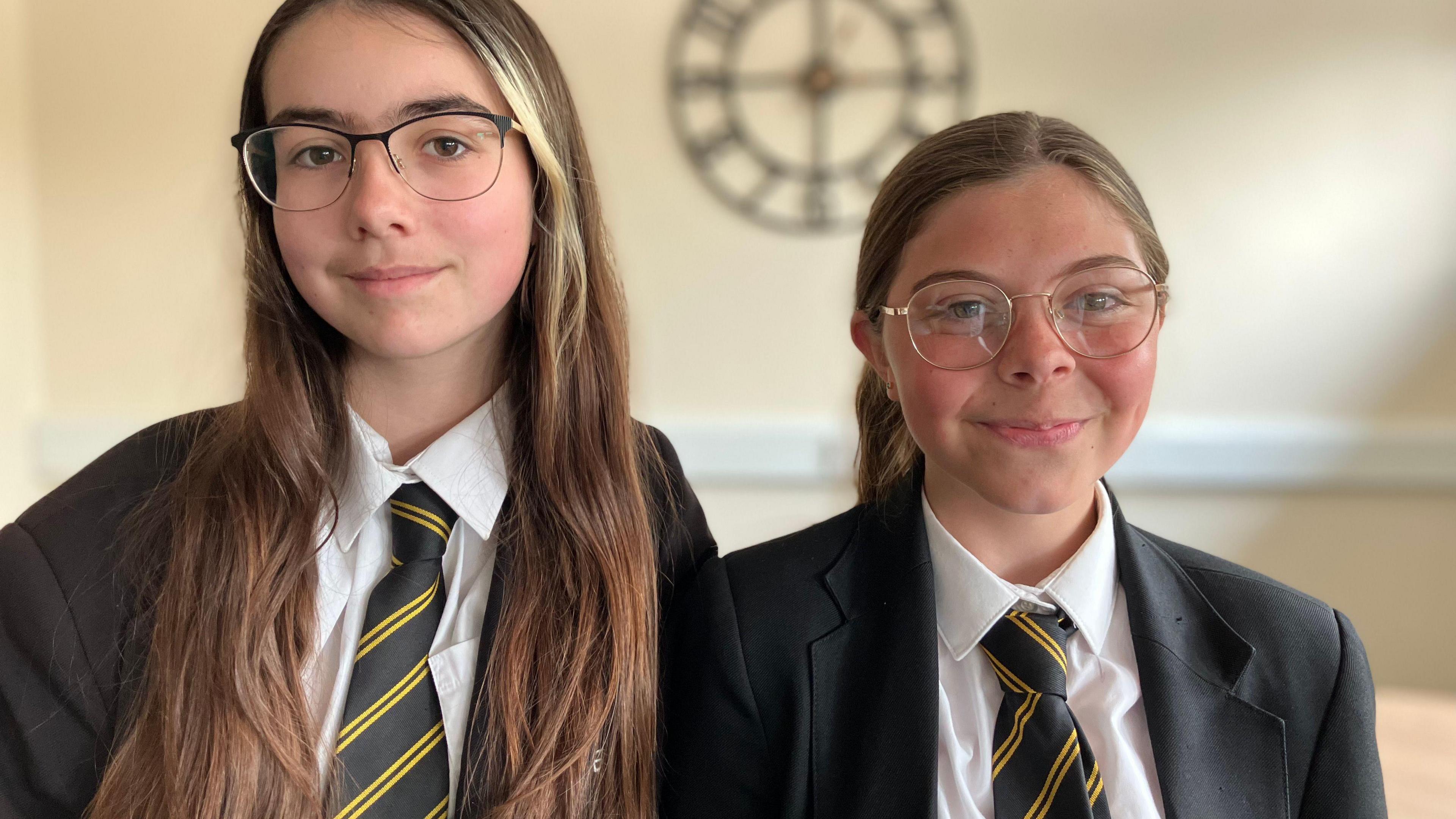 Two school pupils in dark blazers and ties.
