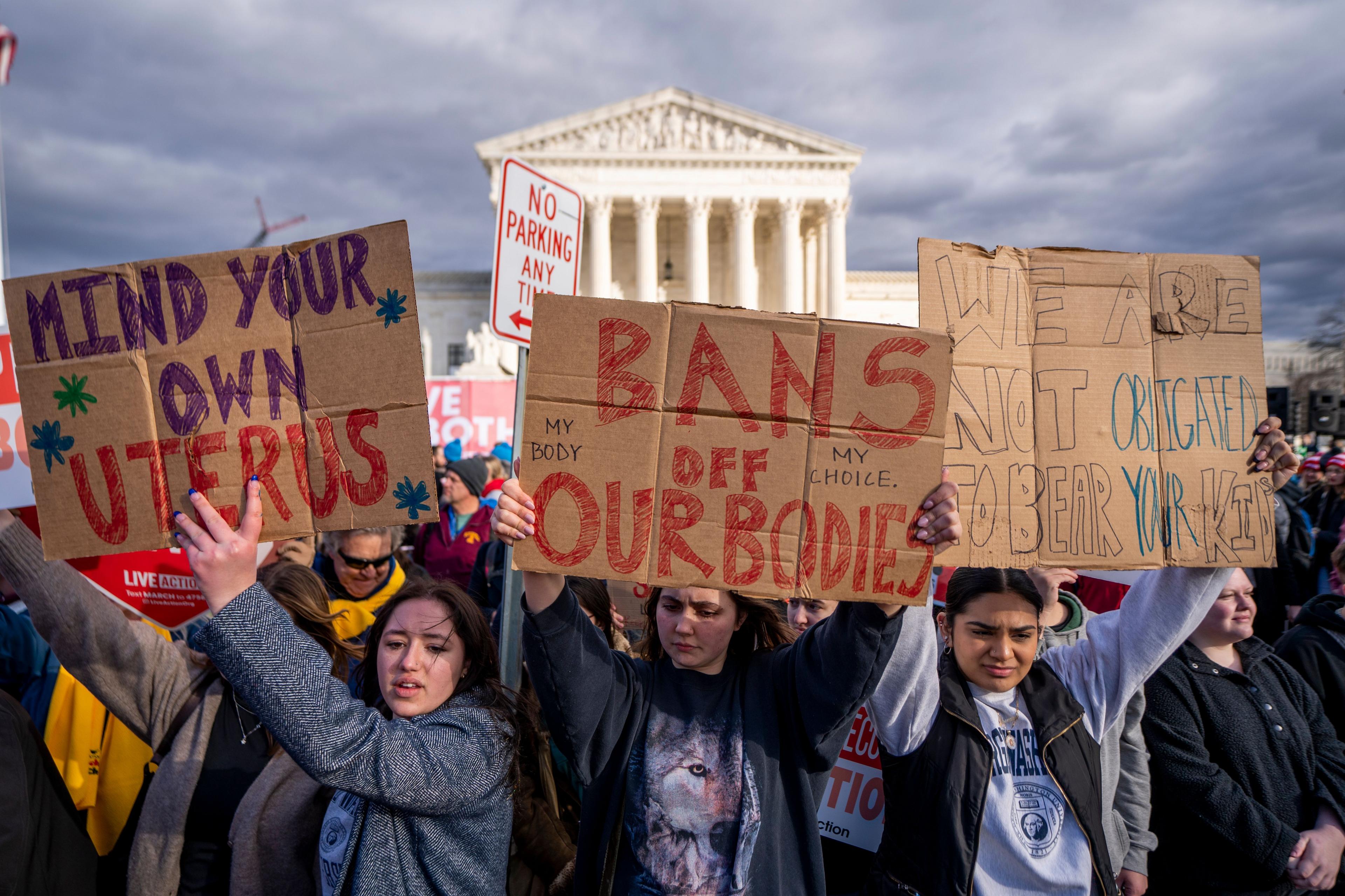 Women hold signs protesting anti-abortion laws