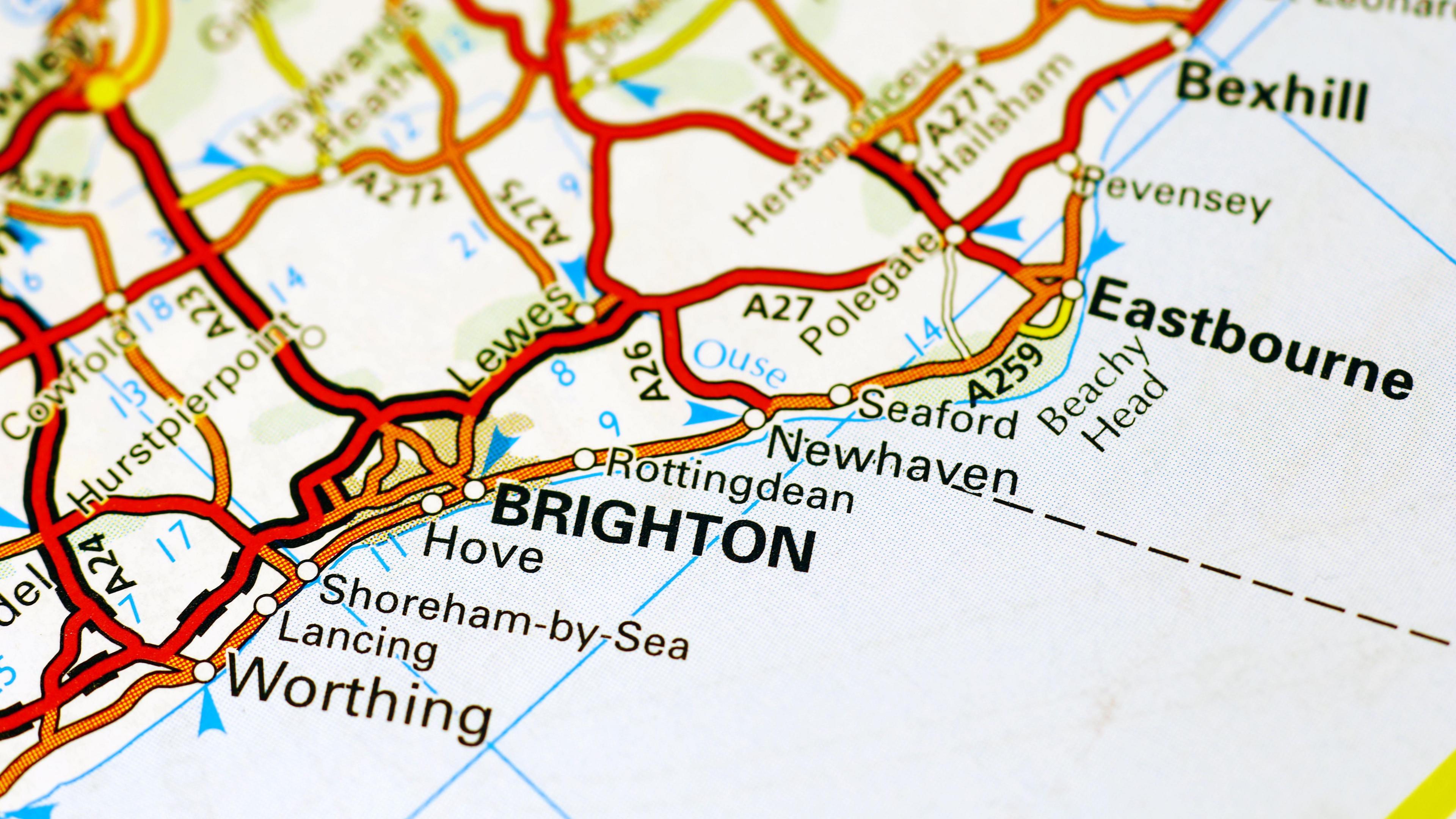 A close up a map shows the Sussex coastline with Brighton in large capital letters at the centre. In the left-hand foreground we see the names of Hove, Shoreham-by Sea, Lancing and Worthing to the west. In the top right-hand side we see Rottingdean, Newhaven and Seaford named and further into the distance Eastbourne, Pevensey and Bexhill.