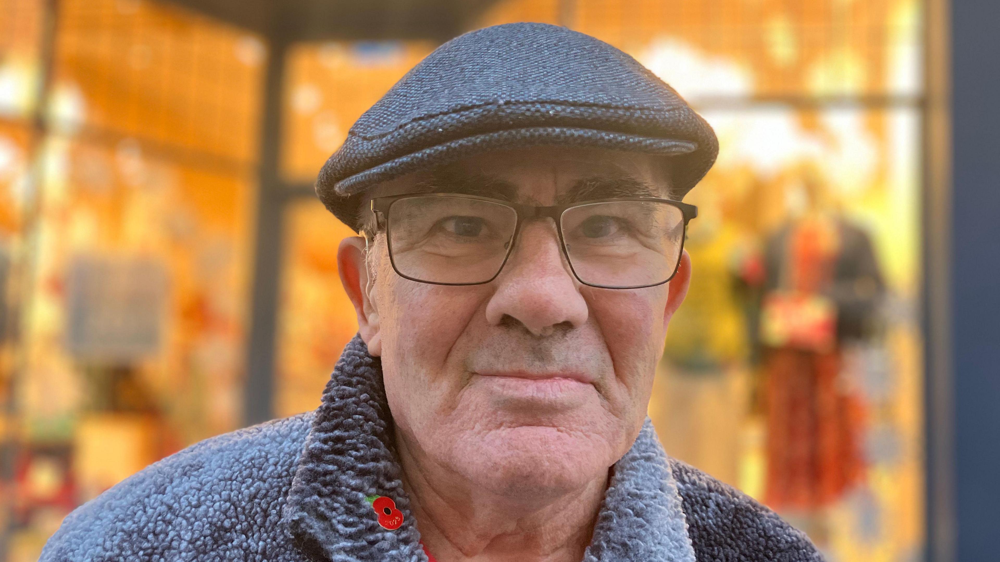 David Shefford is wearing a flat cap and has glasses as he looks into the camera 