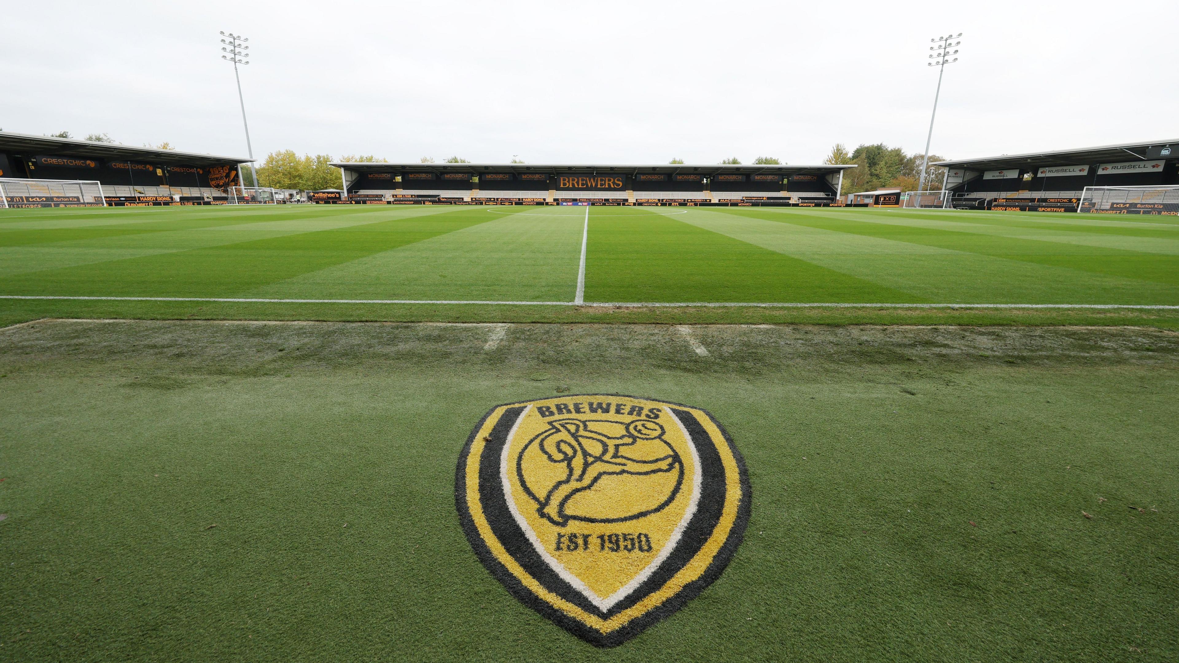 A view of the inside of Burton Albion's Pirelli Stadium with the club emblem beside the pitch