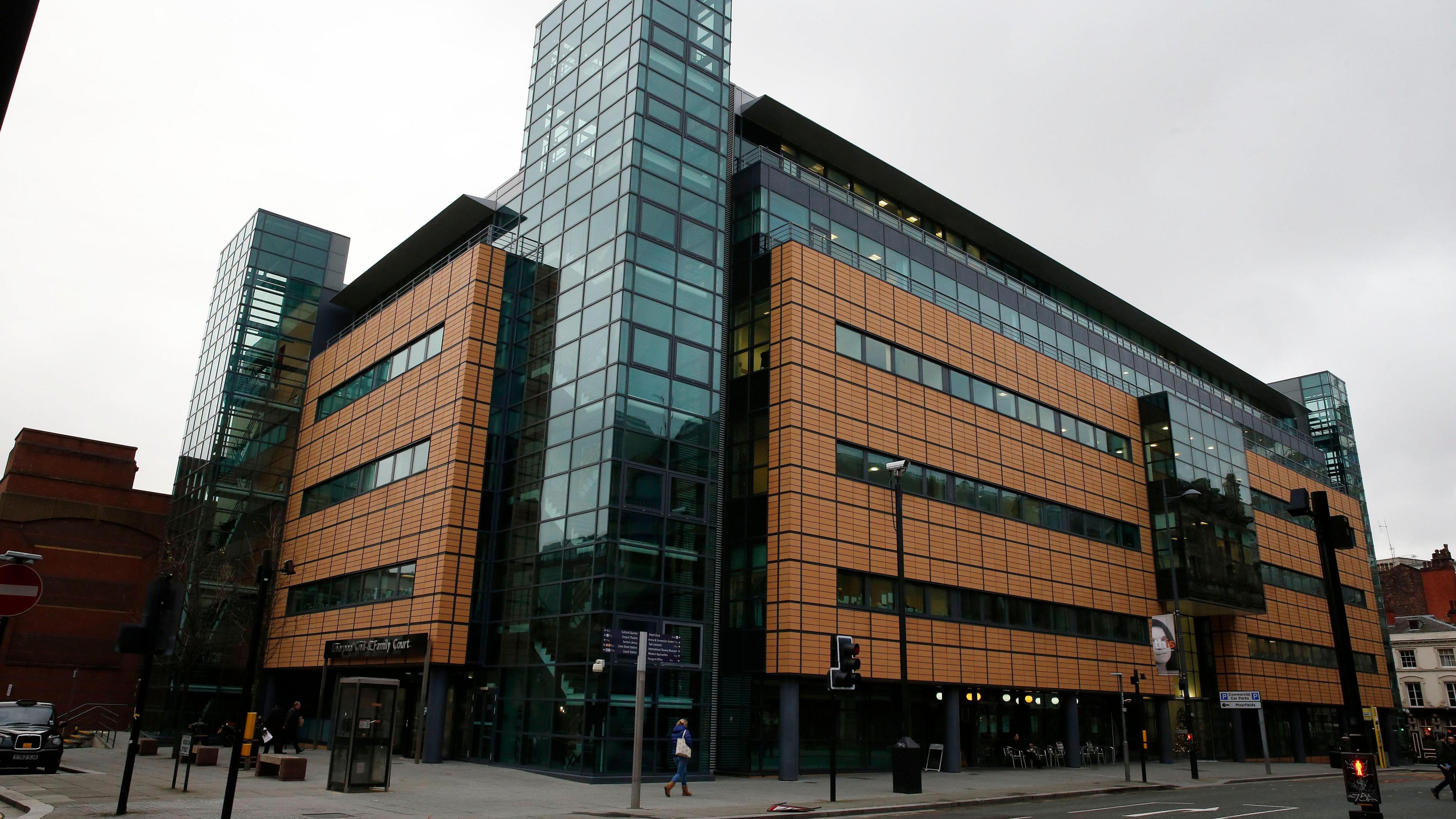 An exterior view of the Liverpool Civil and Family Court centre, which has salmon coloured cladding and glass panelled stairwells. 